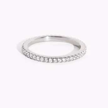 Slim white gold infinity band with delicate round diamonds, featuring continuous pavé design on white background.