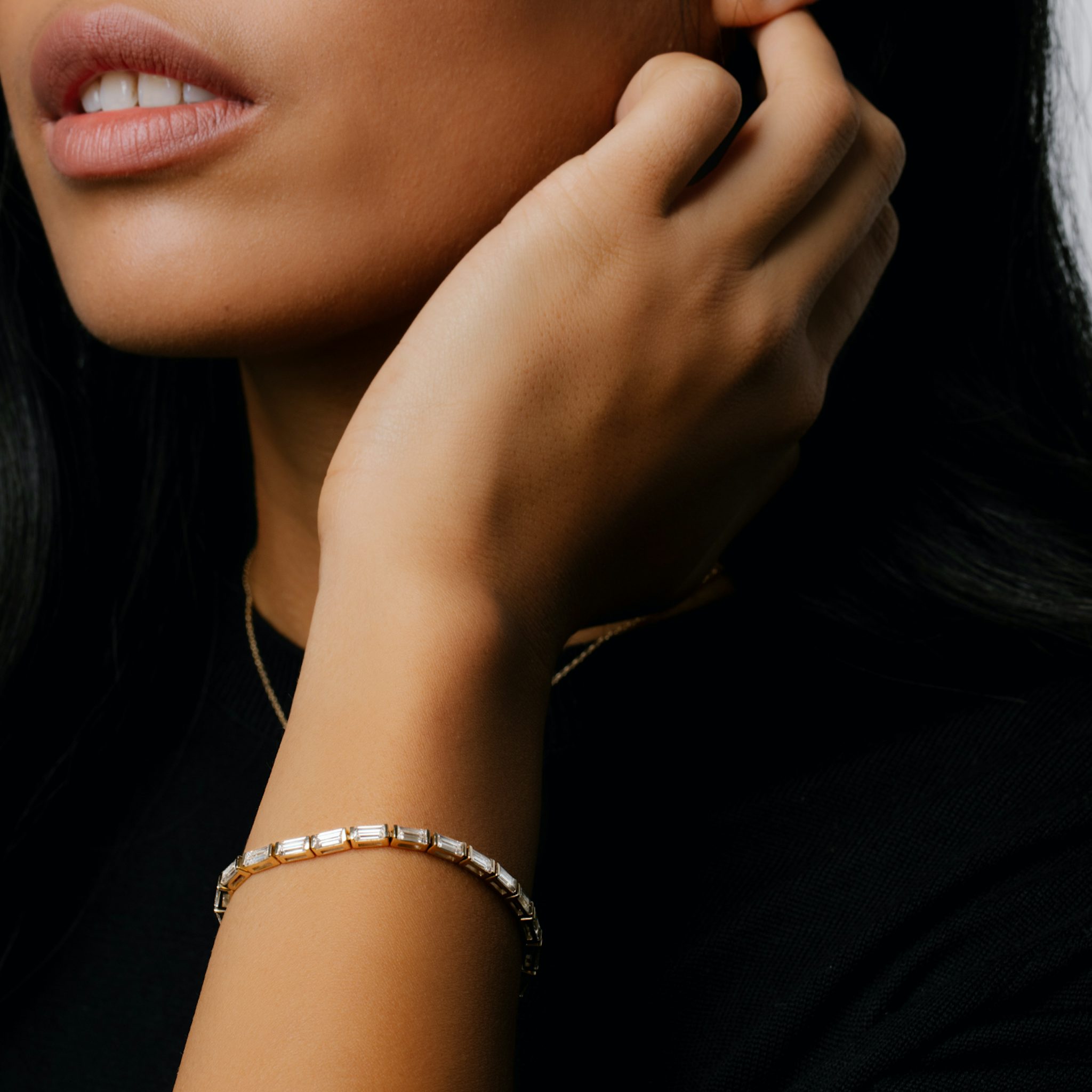 A woman wearing a Baguette Tennis Bracelet, with her hand resting near her ear.