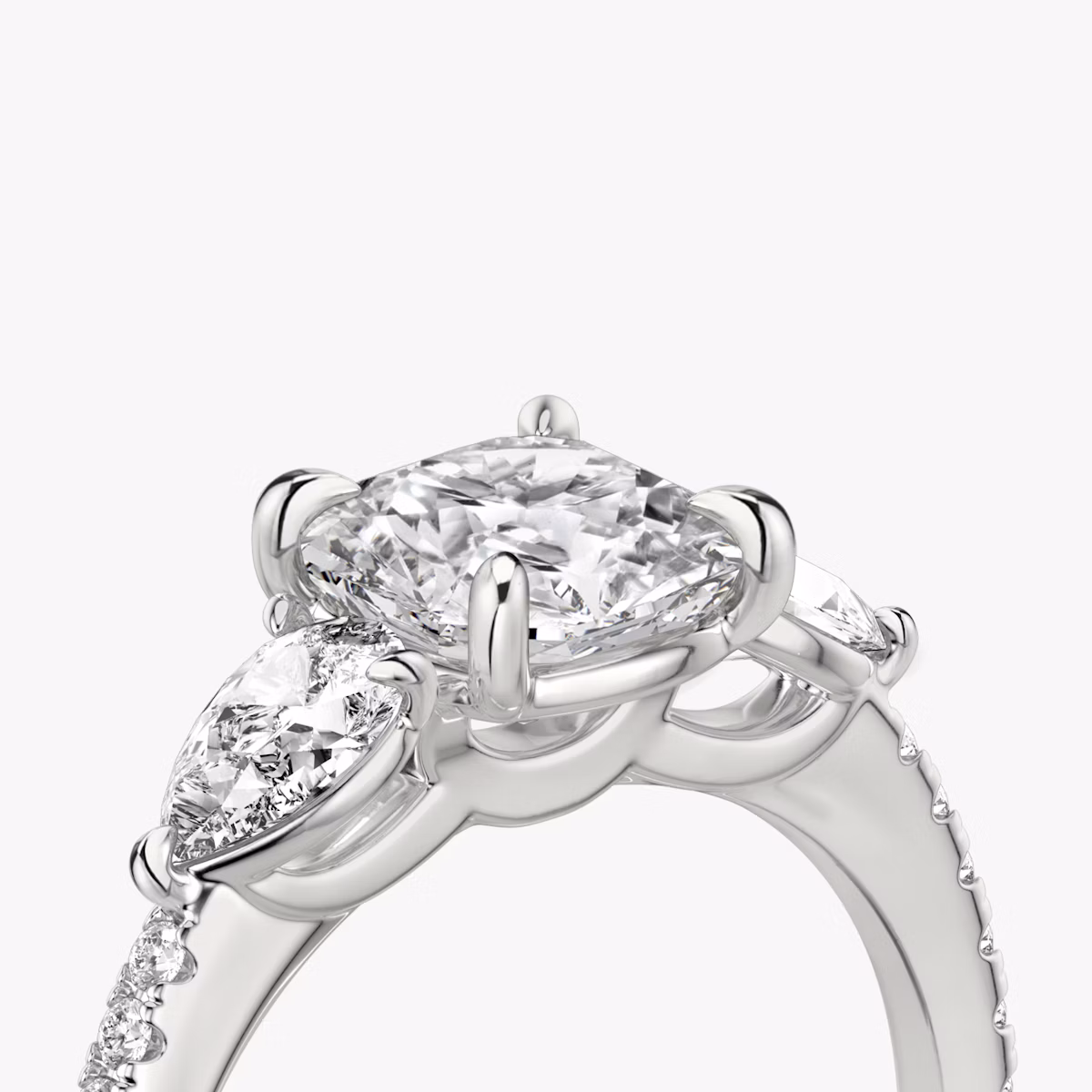 The Three Stone | Cushion | Platinum | bandAccent: Pavé | sideStoneCarat: 0.25ct | sideStoneShape: Pear | diamondOrientation: vertical | caratWeight: other