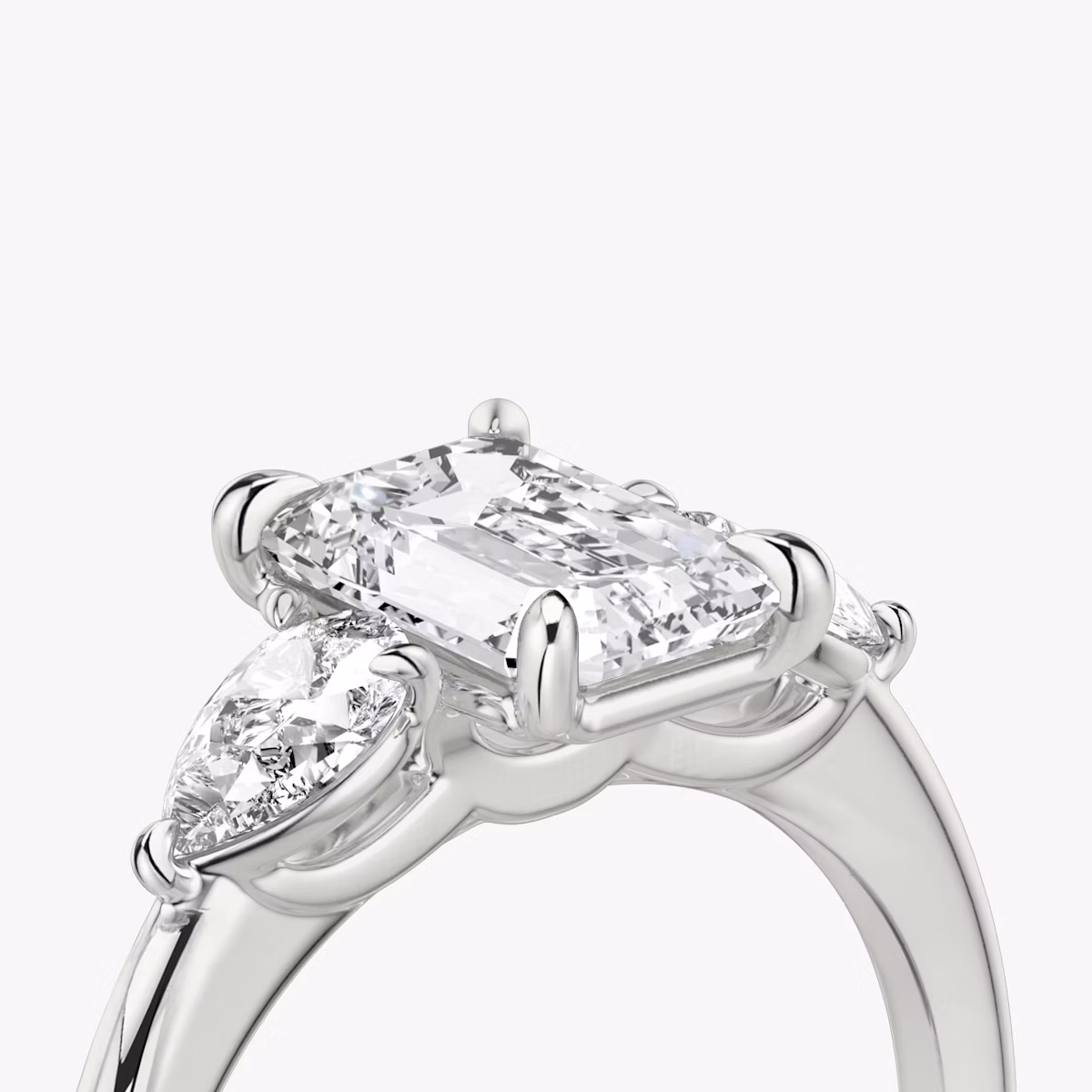 The Three Stone | Emerald | Platinum | bandAccent: Plain | sideStoneCarat: 0.25ct | sideStoneShape: Pear | diamondOrientation: vertical | caratWeight: other