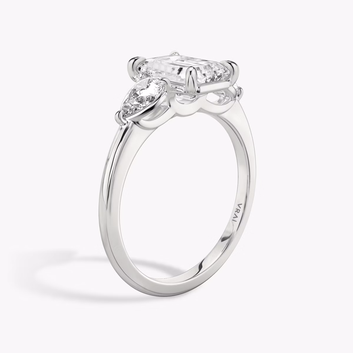 The Three Stone | Emerald | Platinum | bandAccent: Plain | sideStoneCarat: 0.25ct | sideStoneShape: Pear | diamondOrientation: vertical | caratWeight: other