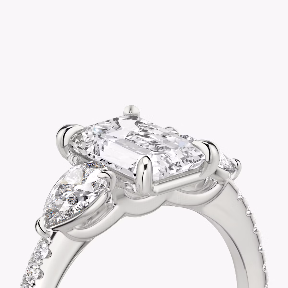 The Three Stone | Emerald | Platinum | bandAccent: Pavé | sideStoneCarat: 0.25ct | sideStoneShape: Pear | diamondOrientation: vertical | caratWeight: other