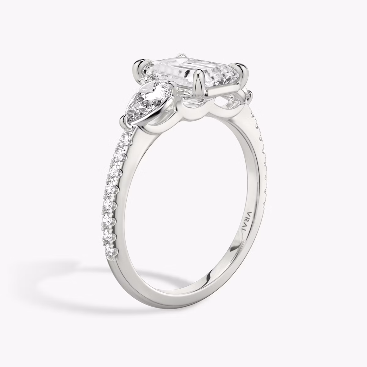 The Three Stone | Emerald | Platinum | bandAccent: Pavé | sideStoneCarat: 0.25ct | sideStoneShape: Pear | diamondOrientation: vertical | caratWeight: other