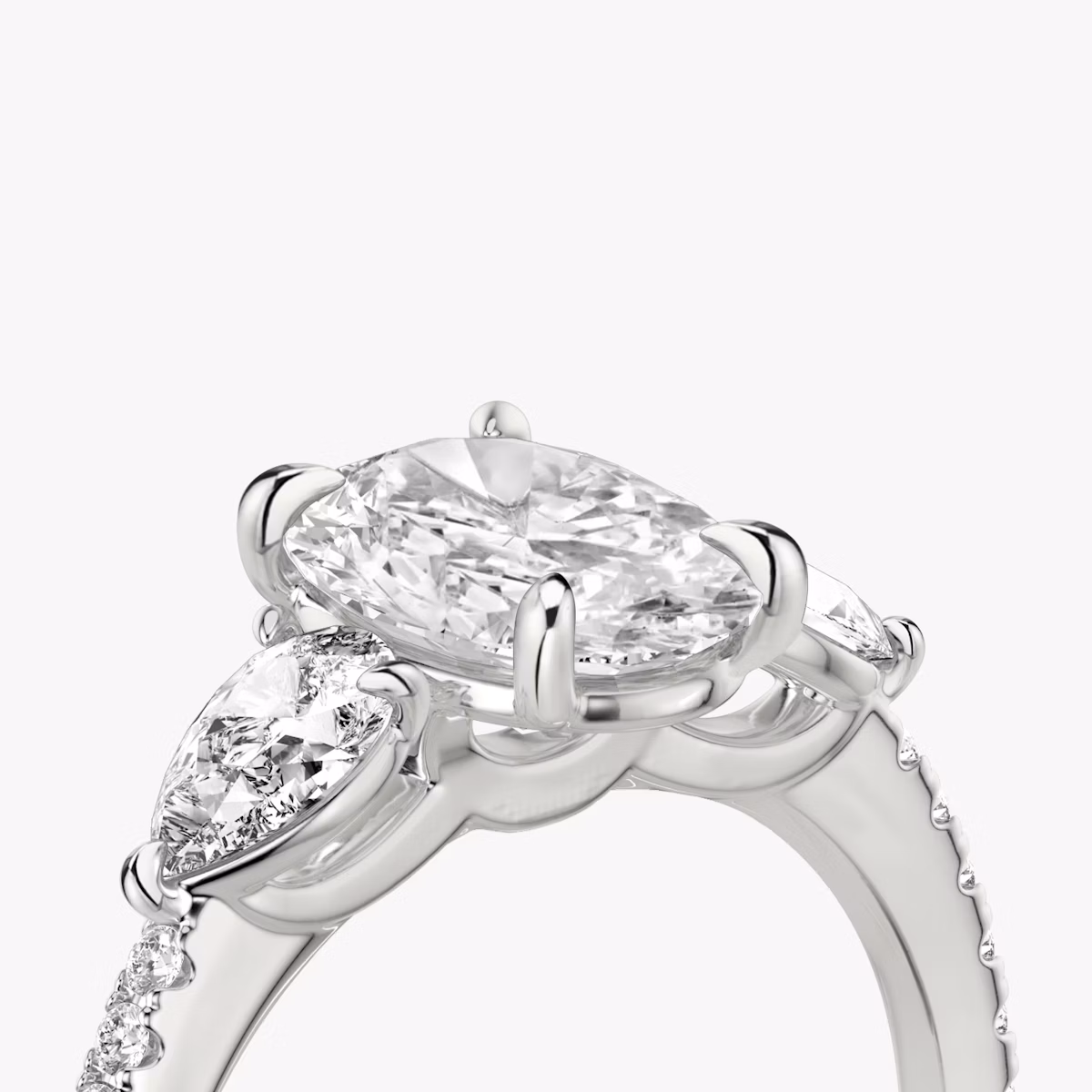 Anillo de compromiso Three Stone | Oval | Platino | bandAccent: Pavé | sideStoneCarat: 0.25ct | sideStoneShape: Pera | diamondOrientation: vertical | caratWeight: other