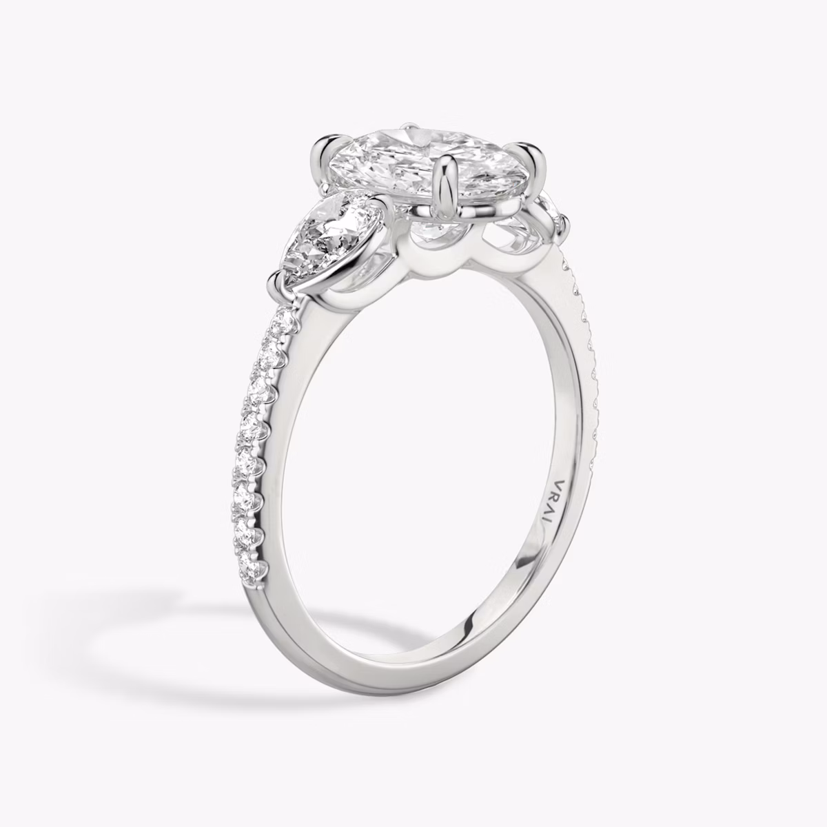 Anillo de compromiso Three Stone | Oval | Platino | bandAccent: Pavé | sideStoneCarat: 0.25ct | sideStoneShape: Pera | diamondOrientation: vertical | caratWeight: other
