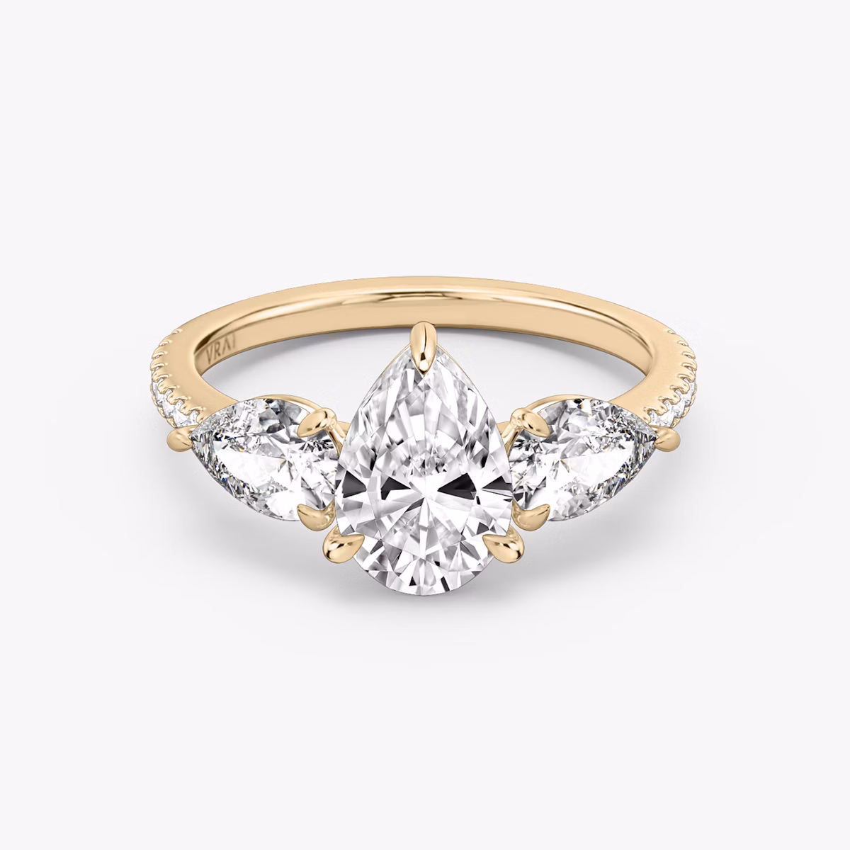 Rose gold pavé ring with pear-cut center diamond and two pear side stones, shown on white background.