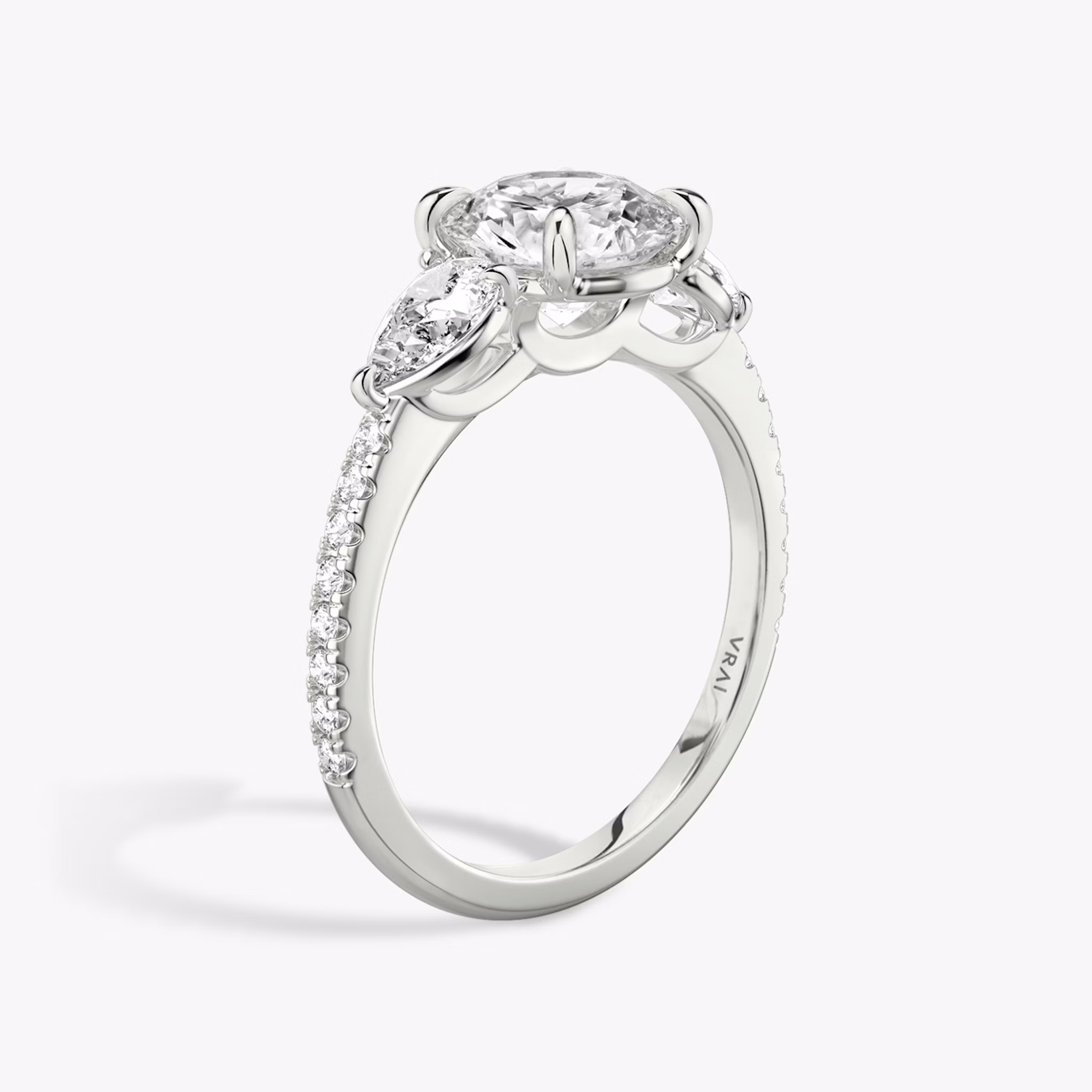 The Three Stone | Round Brilliant | Platinum | bandAccent: Pavé | caratWeight: other | sideStoneCarat: 0.25ct | sideStoneShape: Pear | diamondOrientation: vertical
