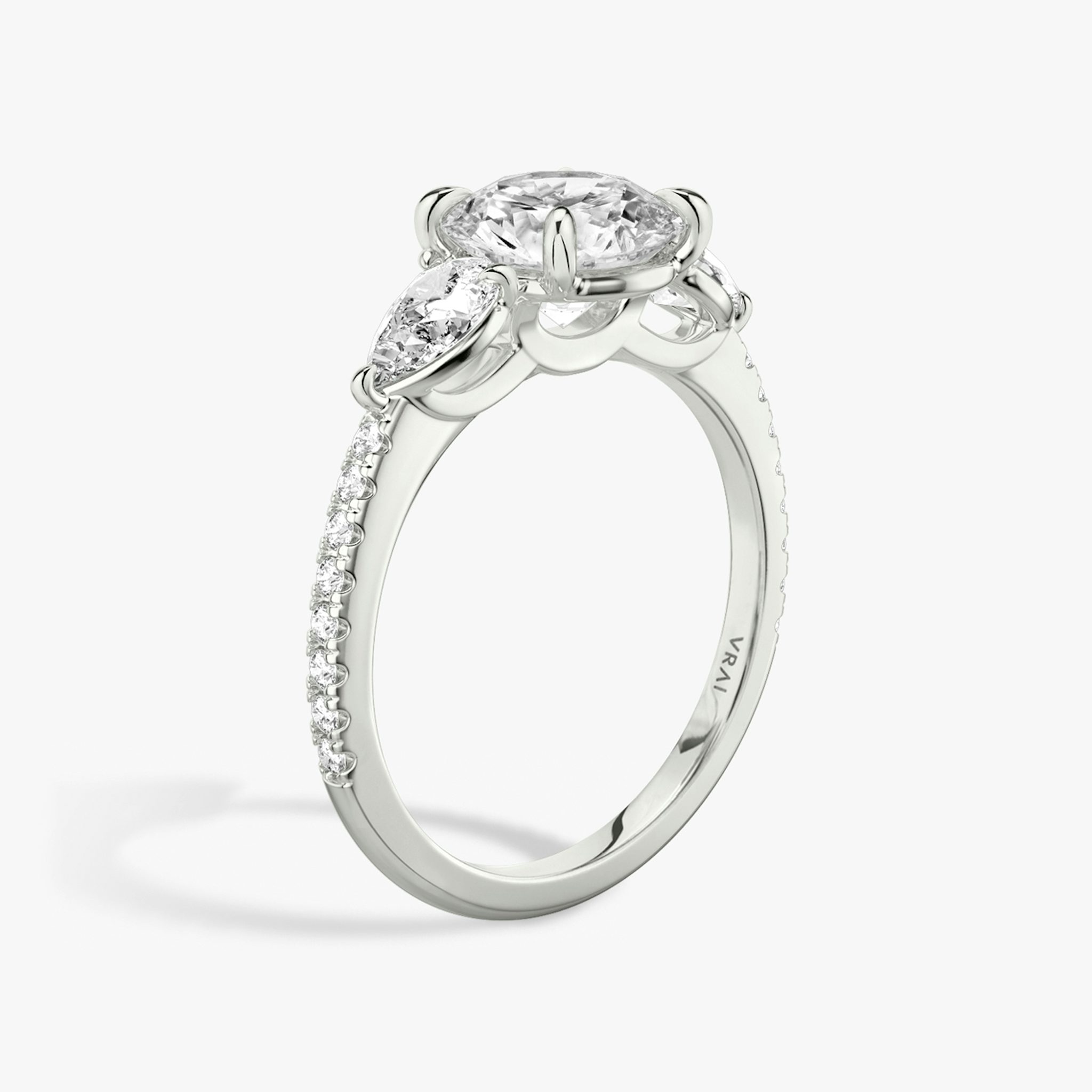 The Three Stone | Round Brilliant | Platinum | bandAccent: Pavé | caratWeight: other | sideStoneCarat: 0.25ct | sideStoneShape: Pear | diamondOrientation: vertical
