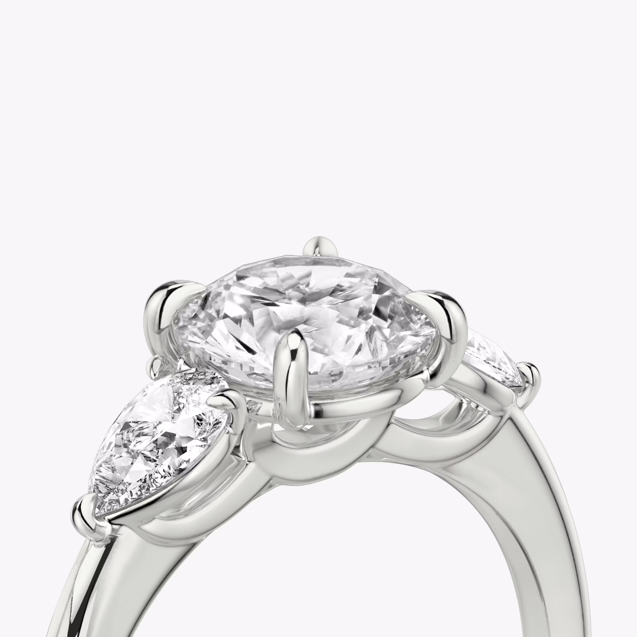 The Three Stone | Round Brilliant | Platinum | bandAccent: Plain | caratWeight: other | sideStoneCarat: 0.25ct | sideStoneShape: Pear | diamondOrientation: vertical
