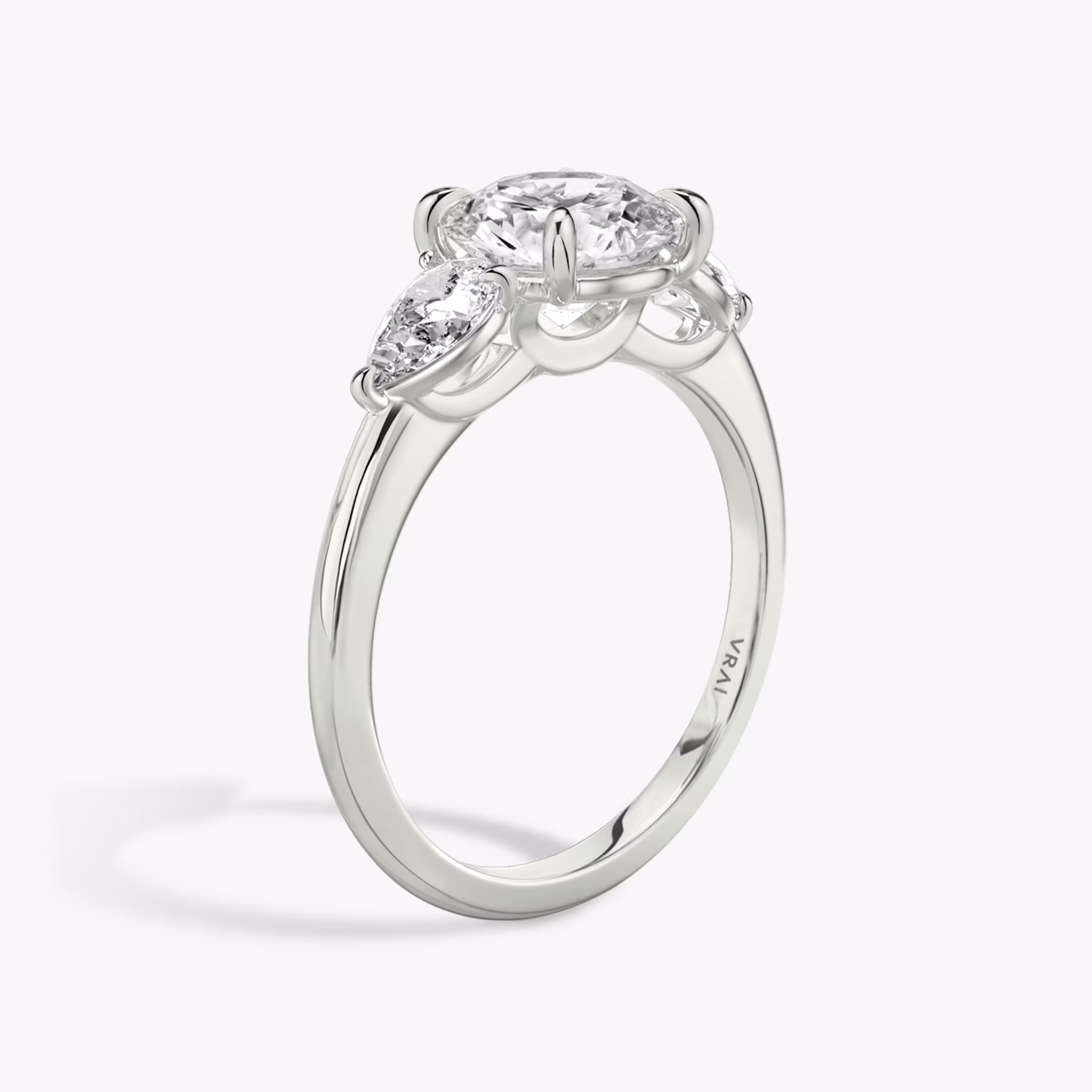 The Three Stone | Round Brilliant | Platinum | bandAccent: Plain | caratWeight: other | sideStoneCarat: 0.25ct | sideStoneShape: Pear | diamondOrientation: vertical