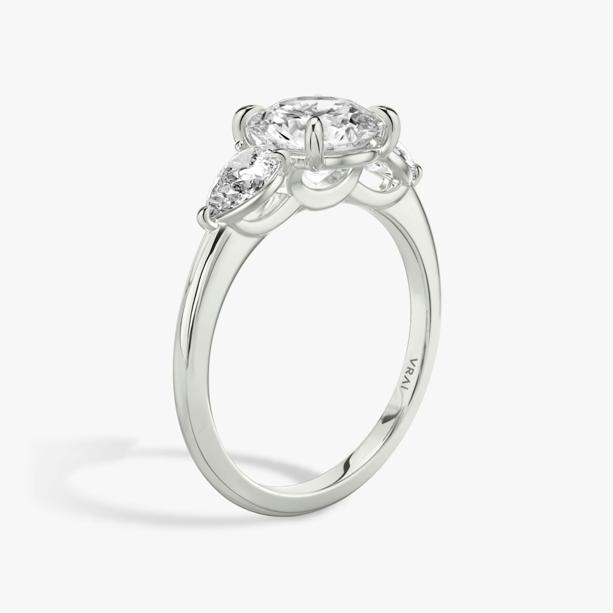 The Three Stone | Round Brilliant | Platinum | bandAccent: Plain | caratWeight: other | sideStoneCarat: 0.25ct | sideStoneShape: Pear | diamondOrientation: vertical