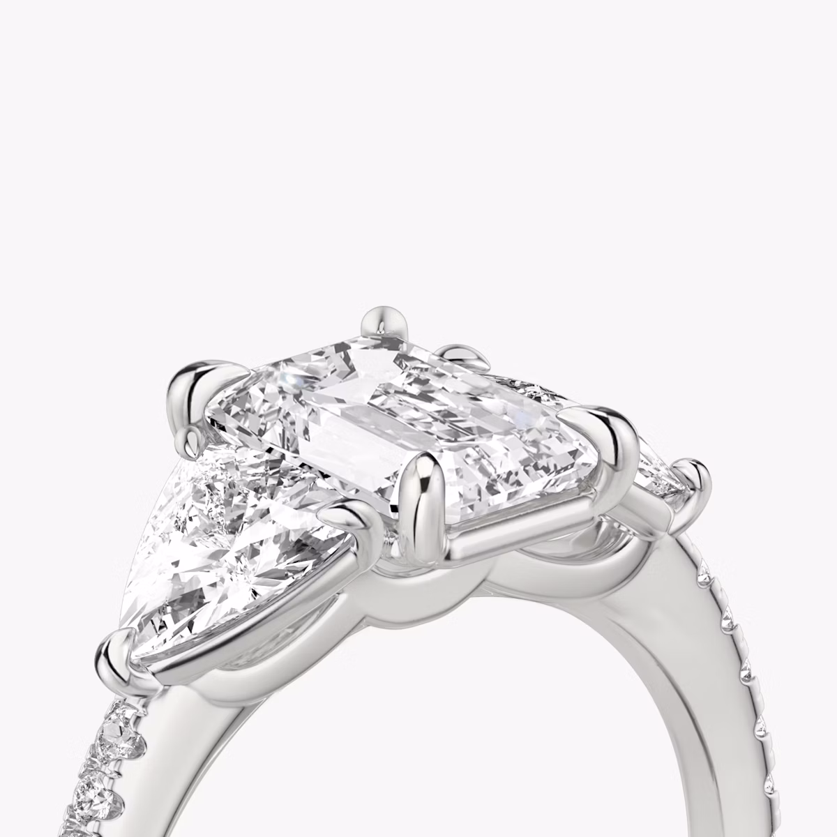 The Three Stone | Emerald | Platinum | bandAccent: Pavé | sideStoneCarat: 0.50ct | sideStoneShape: Trillion | diamondOrientation: vertical | caratWeight: other