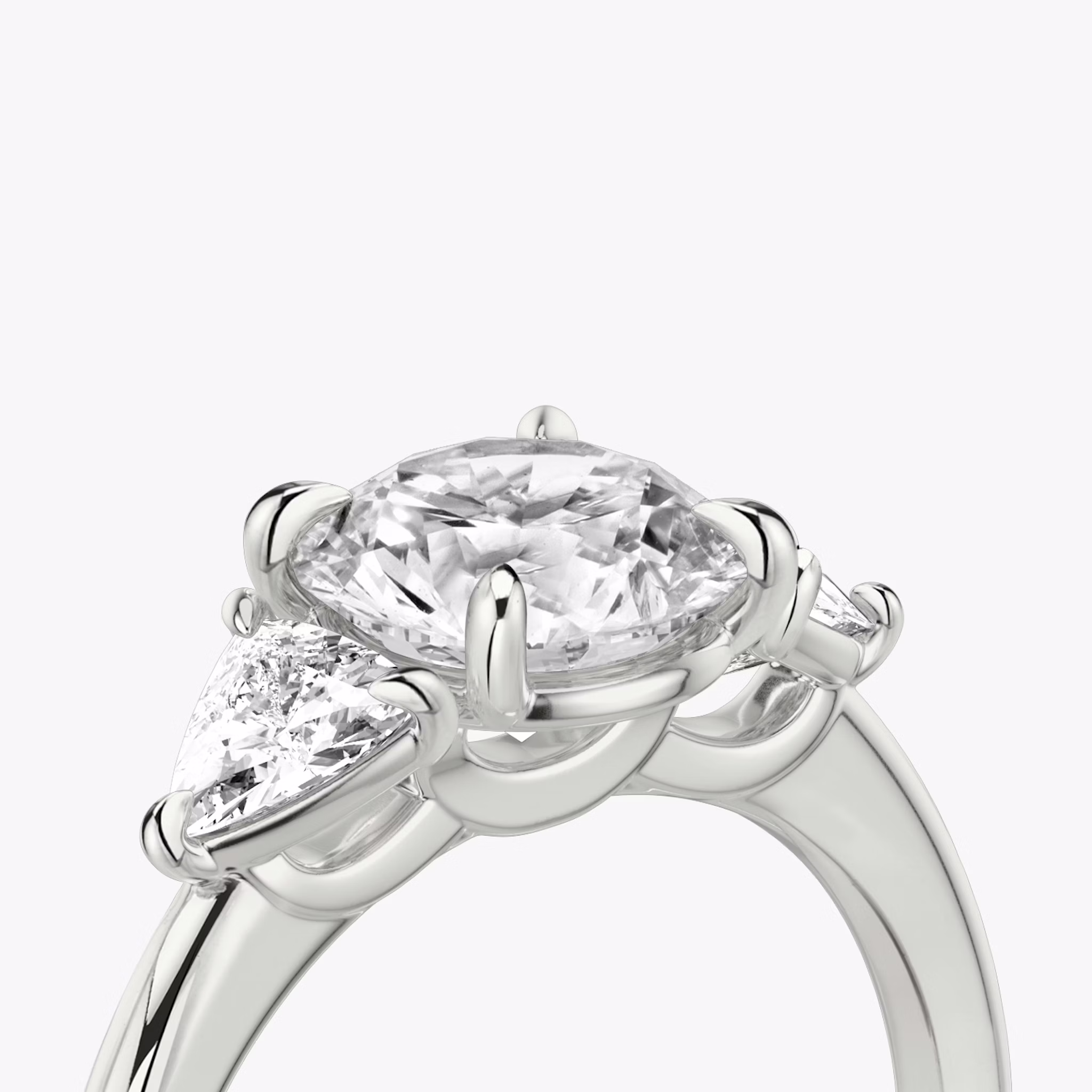 The Three Stone | Round Brilliant | 18k | White Gold | bandAccent: Plain | caratWeight: other | sideStoneCarat: 0.25ct | sideStoneShape: Trillion | diamondOrientation: vertical