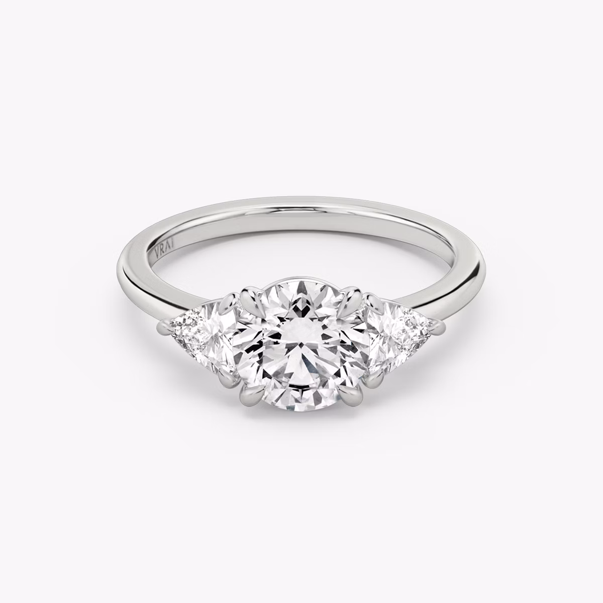 The Three Stone | Round Brilliant | 18k | White Gold | bandAccent: Plain | caratWeight: other | sideStoneCarat: 0.25ct | sideStoneShape: Trillion | diamondOrientation: vertical