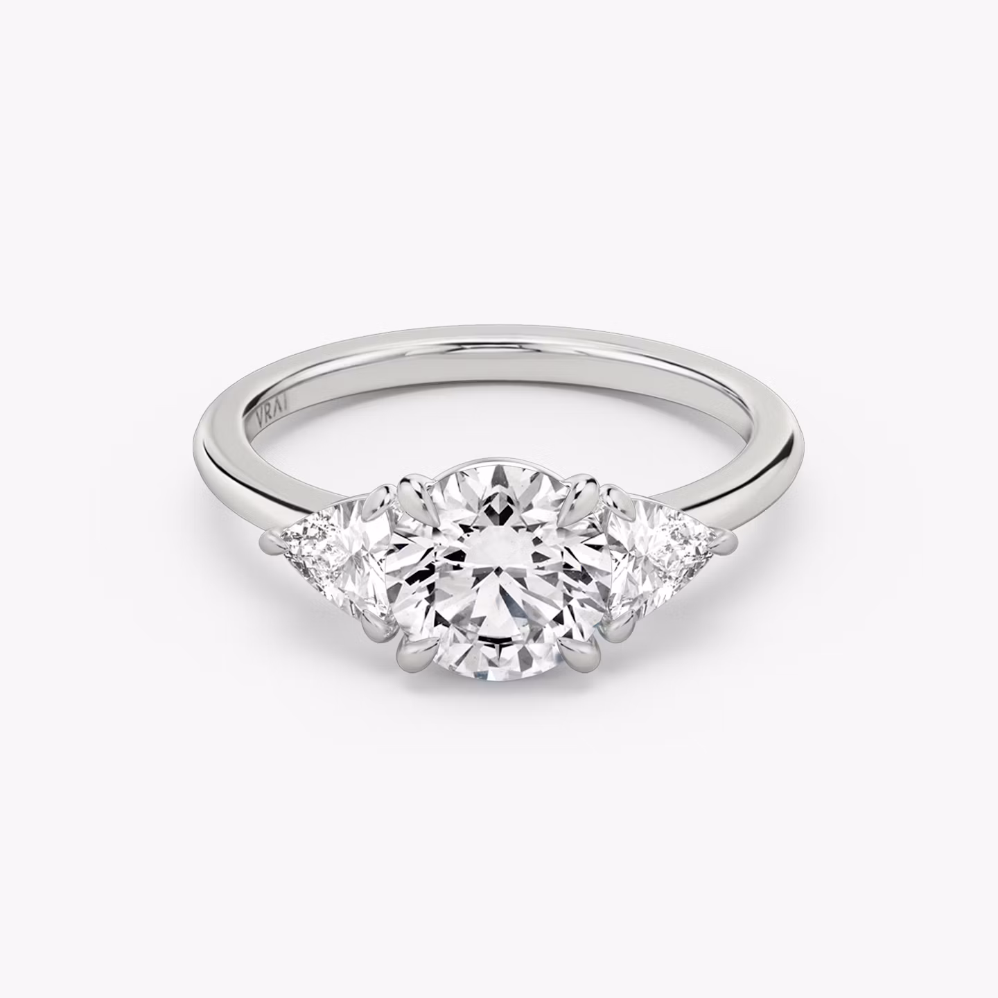 The Three Stone | Round Brilliant | 18k | White Gold | bandAccent: Plain | caratWeight: other | sideStoneCarat: 0.25ct | sideStoneShape: Trillion | diamondOrientation: vertical