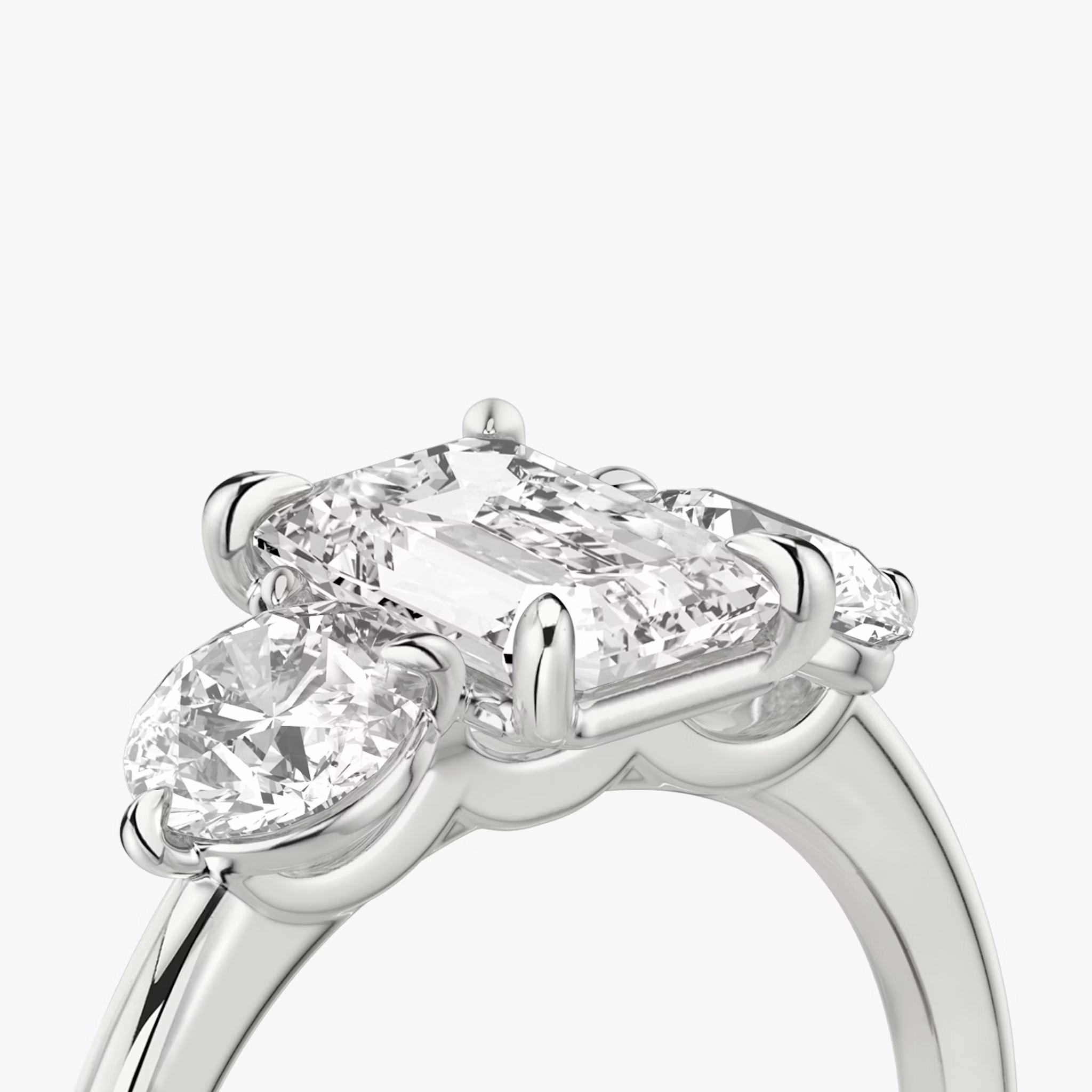 The Three Stone | Emerald | Platinum | bandAccent: Plain | sideStoneCarat: 0.50ct | sideStoneShape: Round Brilliant | diamondOrientation: vertical | caratWeight: other