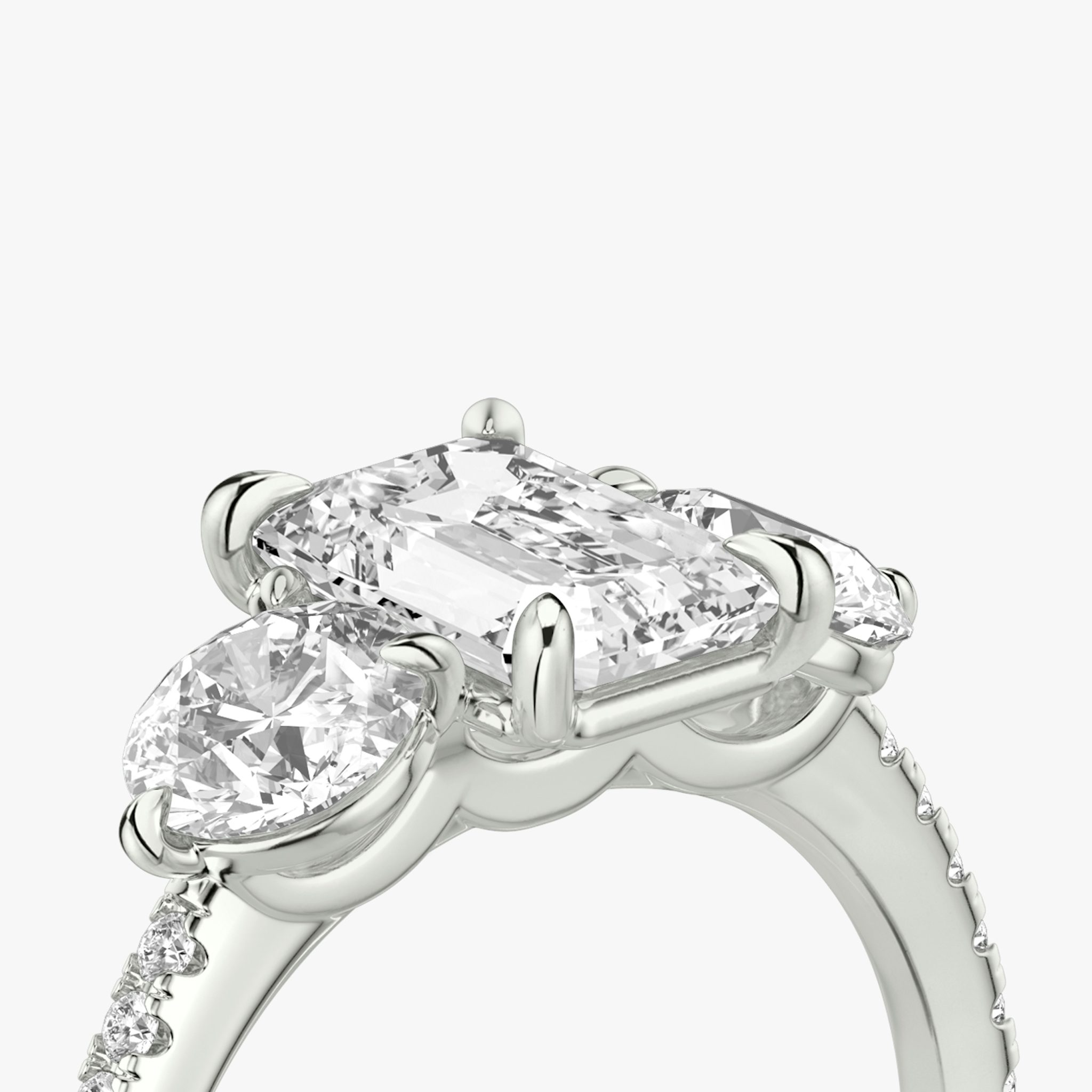 The Three Stone | Emerald | Platinum | bandAccent: Pavé | sideStoneCarat: 0.50ct | sideStoneShape: Round Brilliant | diamondOrientation: vertical | caratWeight: other