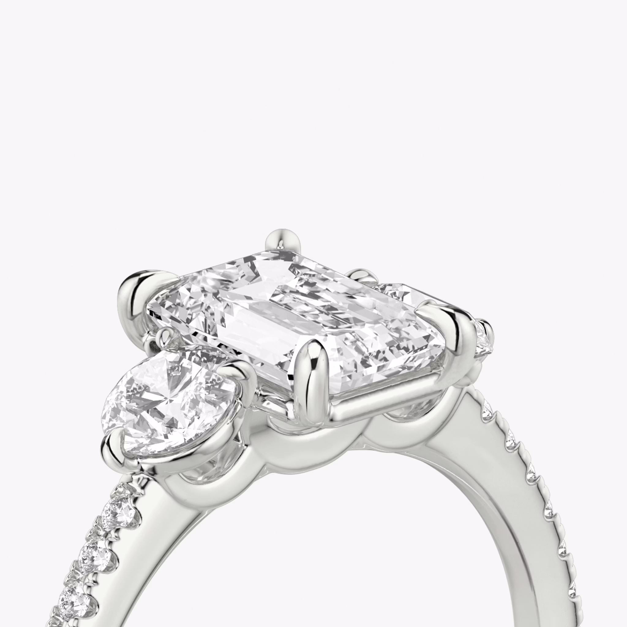 The Three Stone | Emerald | Platinum | bandAccent: Pavé | sideStoneCarat: 0.25ct | sideStoneShape: Round Brilliant | diamondOrientation: vertical | caratWeight: other