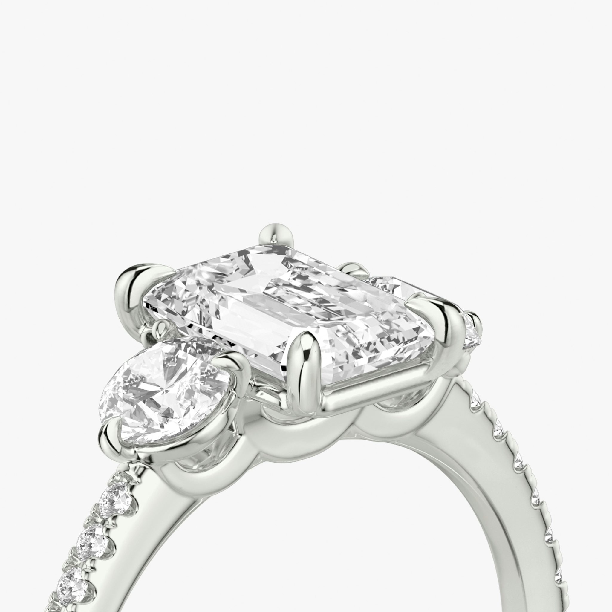 The Three Stone | Emerald | Platinum | bandAccent: Pavé | sideStoneCarat: 0.25ct | sideStoneShape: Round Brilliant | diamondOrientation: vertical | caratWeight: other