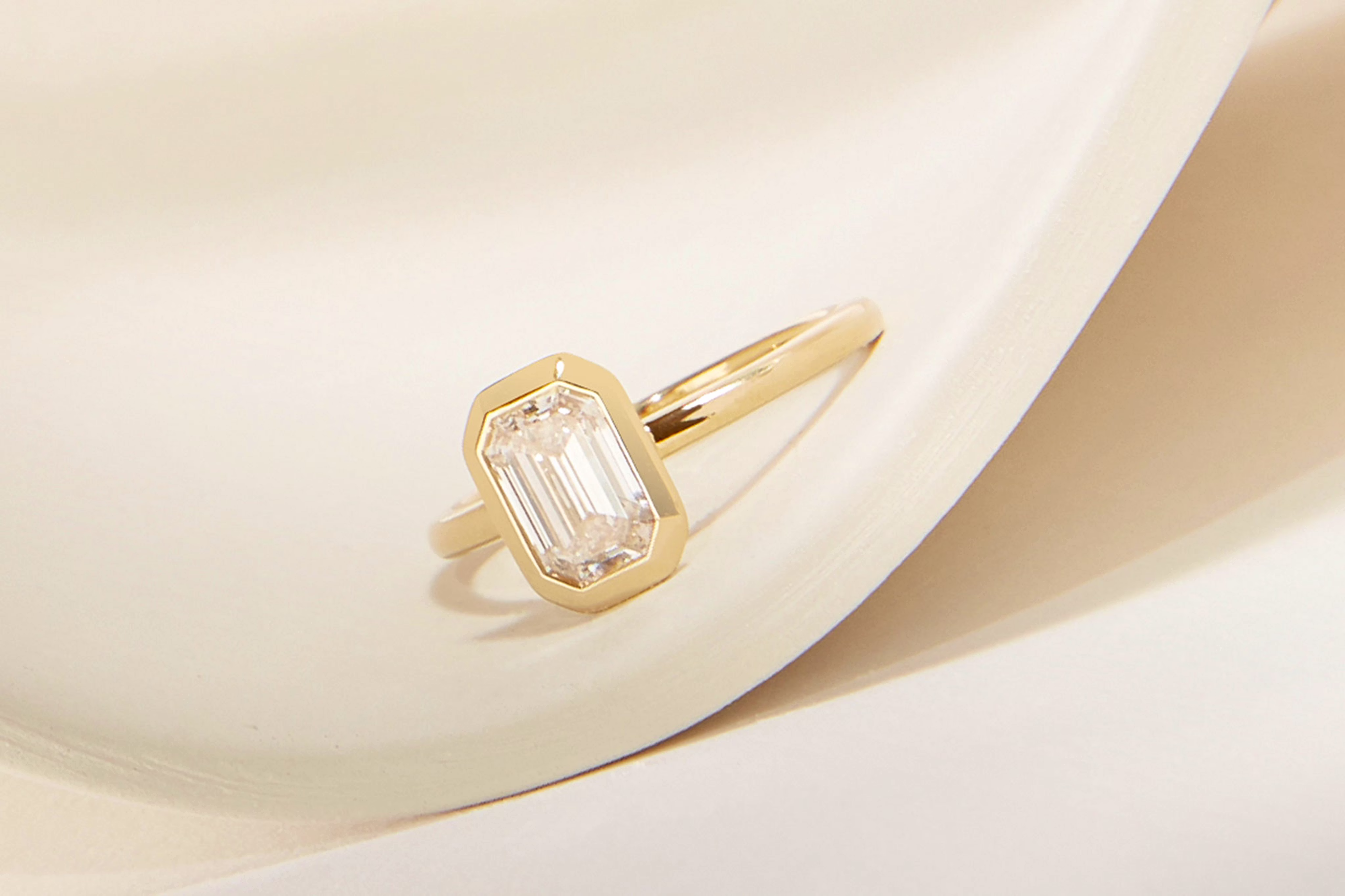 The emerald signature bezel engagement ring with yellow gold band