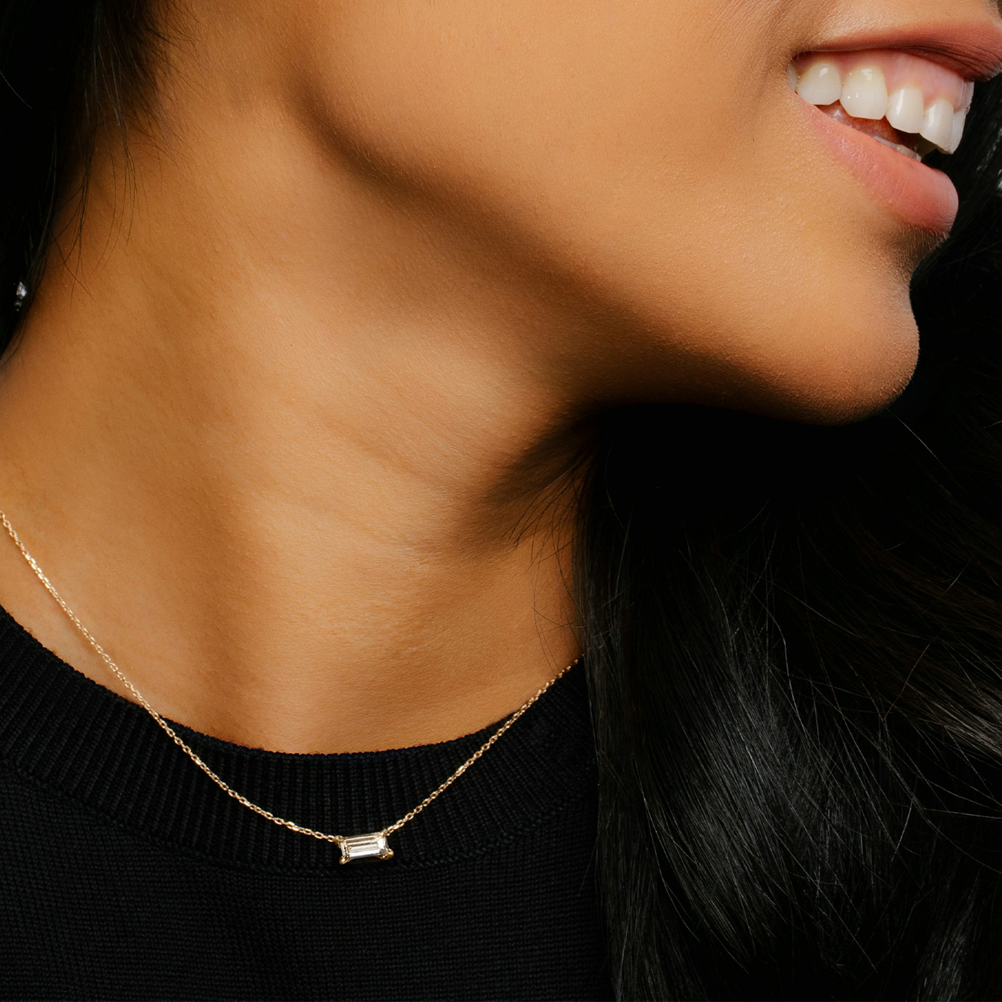 golden necklace with a baguette shaped diamond on a woman's neck