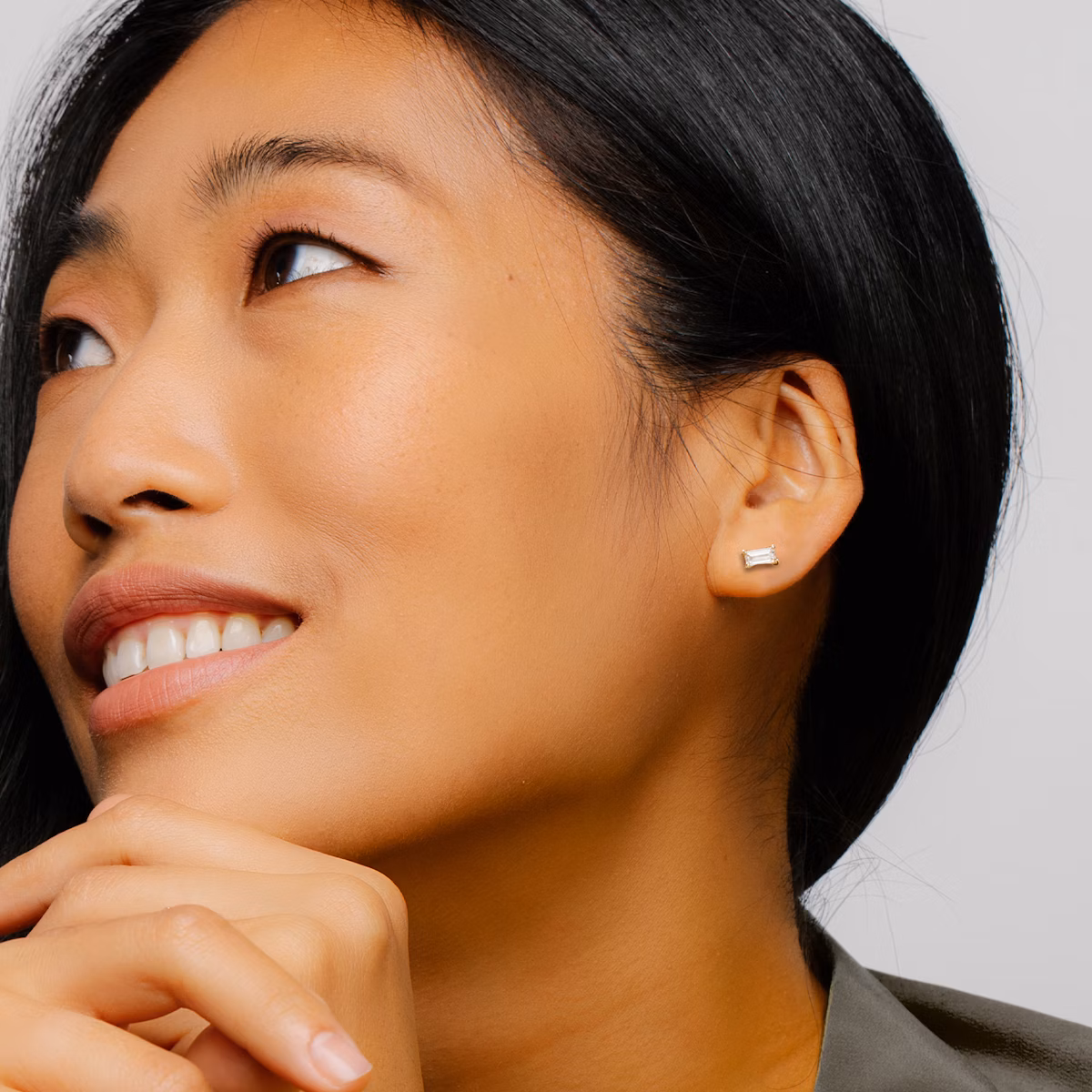 smiling woman shows a stud with a baguette shaped diamond on her left ear