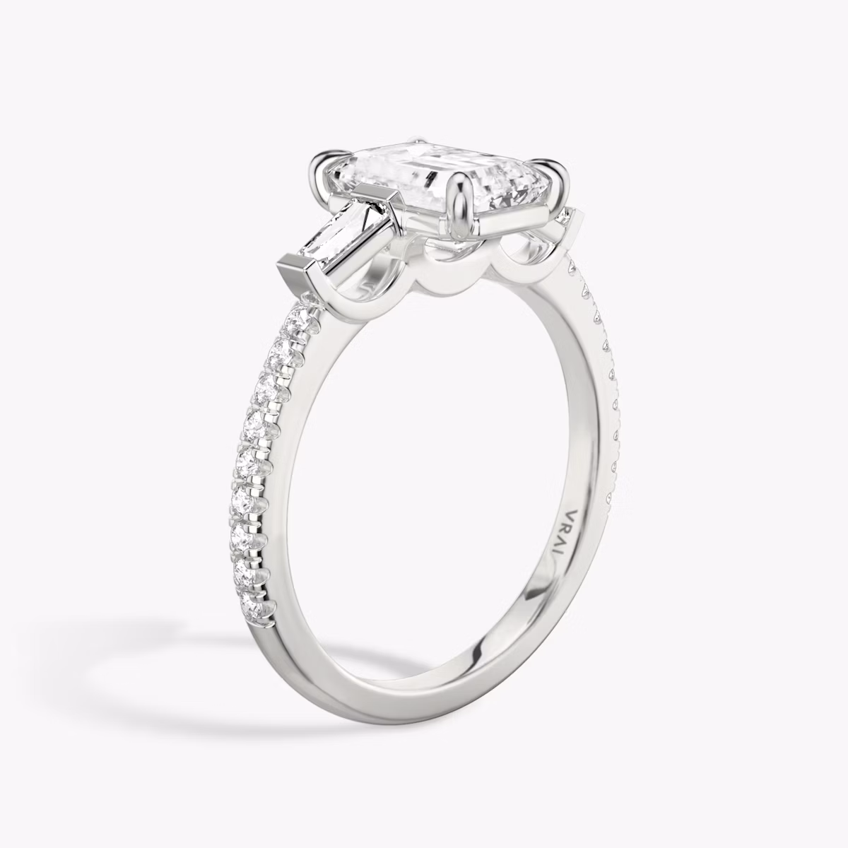 The Three Stone | Emerald | Platinum | bandAccent: Pavé | sideStoneCarat: 0.10ct | sideStoneShape: Tapered Baguette | diamondOrientation: vertical | caratWeight: other