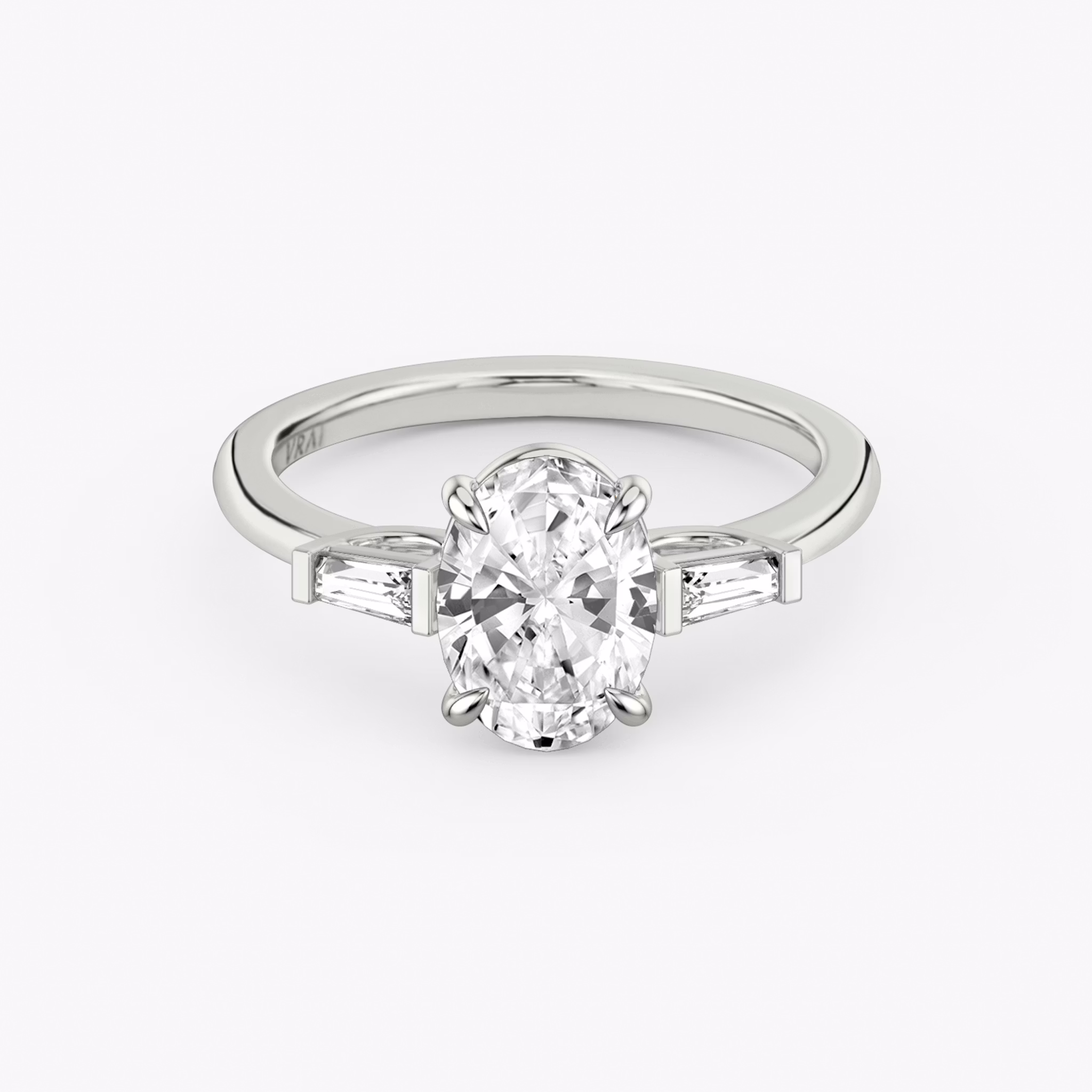 The Three Stone | Oval | 18k | White Gold | bandAccent: Plain | sideStoneCarat: 0.10ct | sideStoneShape: Tapered Baguette | diamondOrientation: vertical | caratWeight: other
