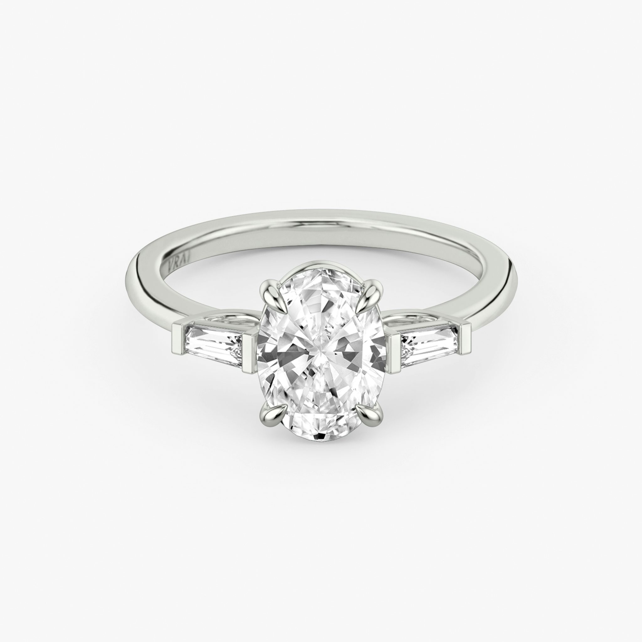 The Three Stone | Oval | 18k | White Gold | bandAccent: Plain | sideStoneCarat: 0.10ct | sideStoneShape: Tapered Baguette | diamondOrientation: vertical | caratWeight: other