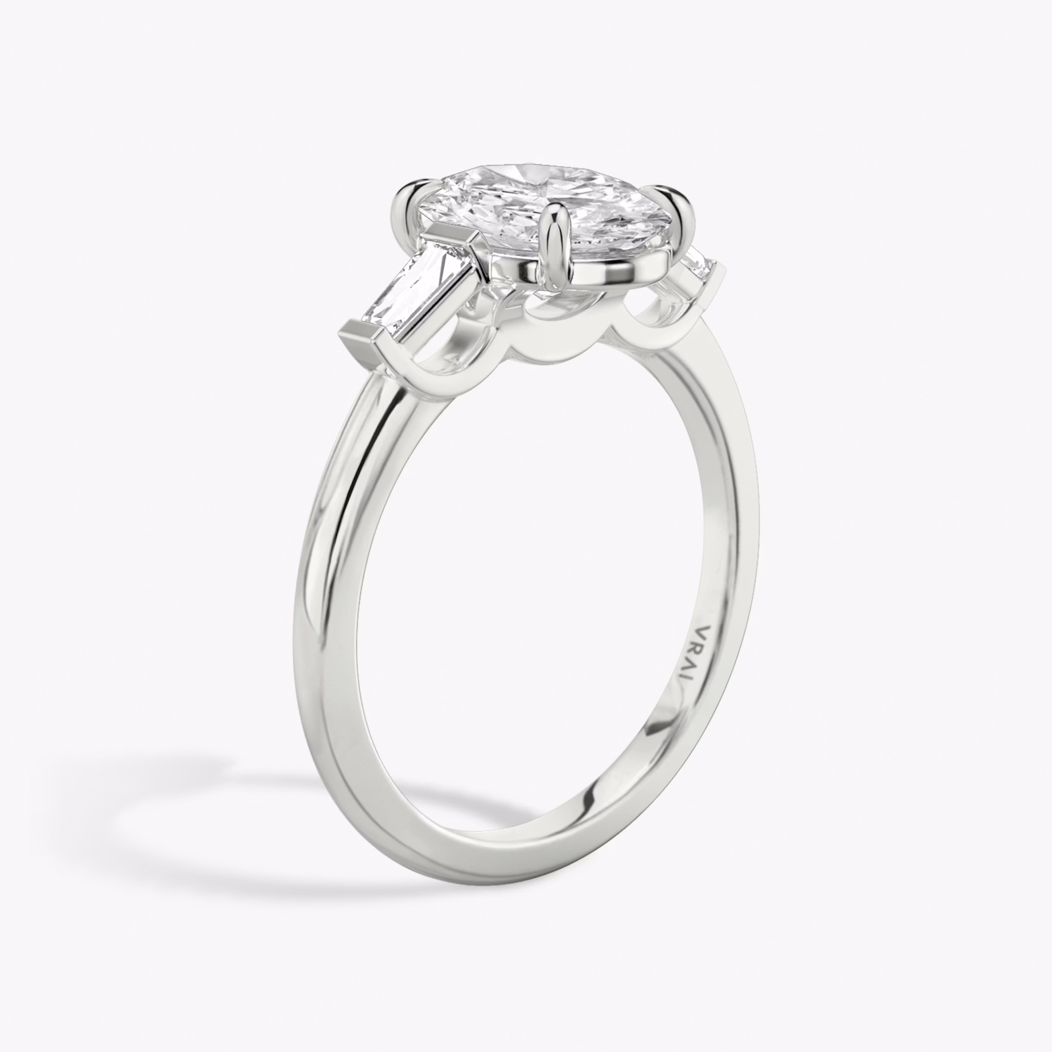 The Three Stone | Oval | 18k | White Gold | bandAccent: Plain | sideStoneCarat: 0.10ct | sideStoneShape: Tapered Baguette | diamondOrientation: vertical | caratWeight: other