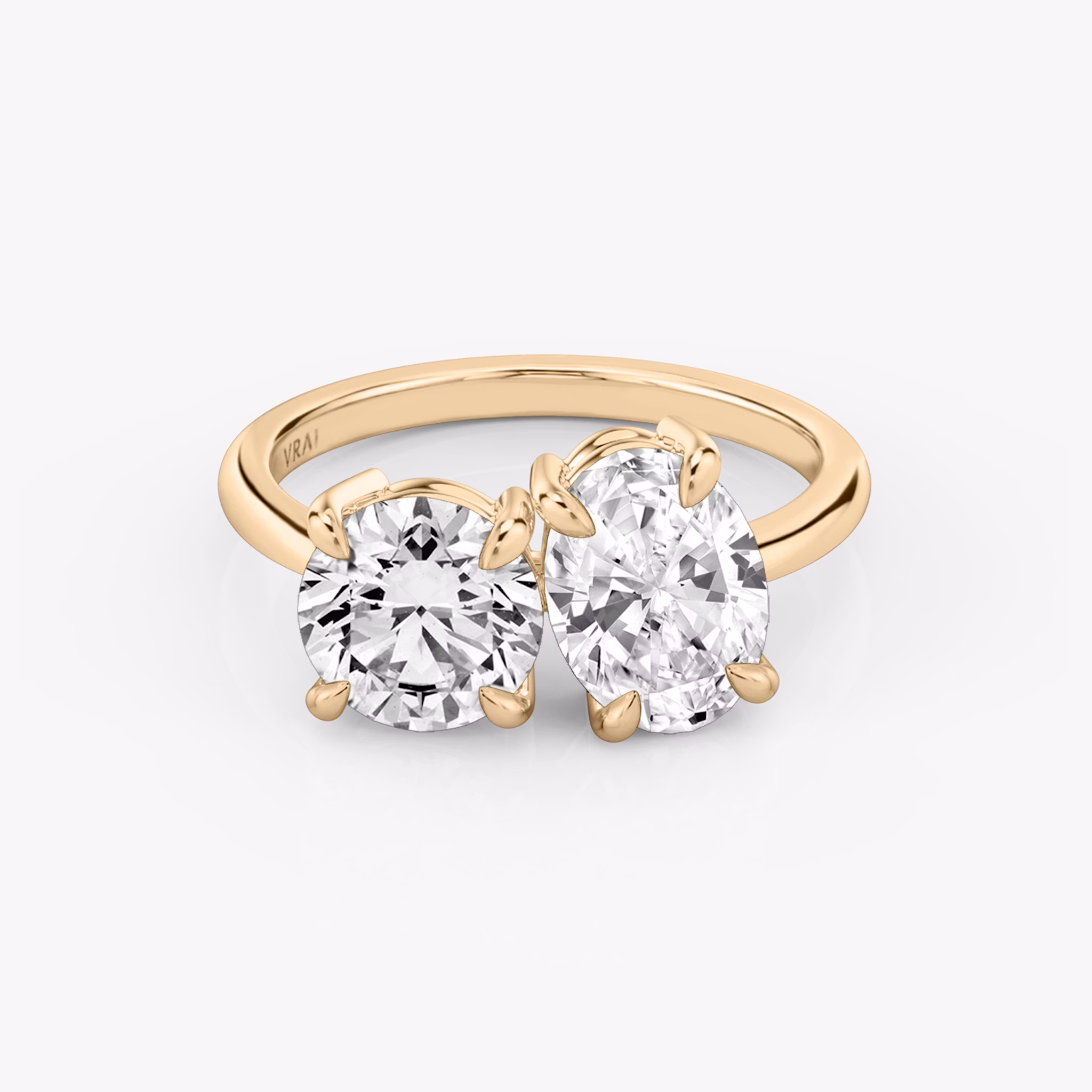 Front view of the Toi et Moi ring in rose gold with round brilliant and oval-cut diamonds on a white background.