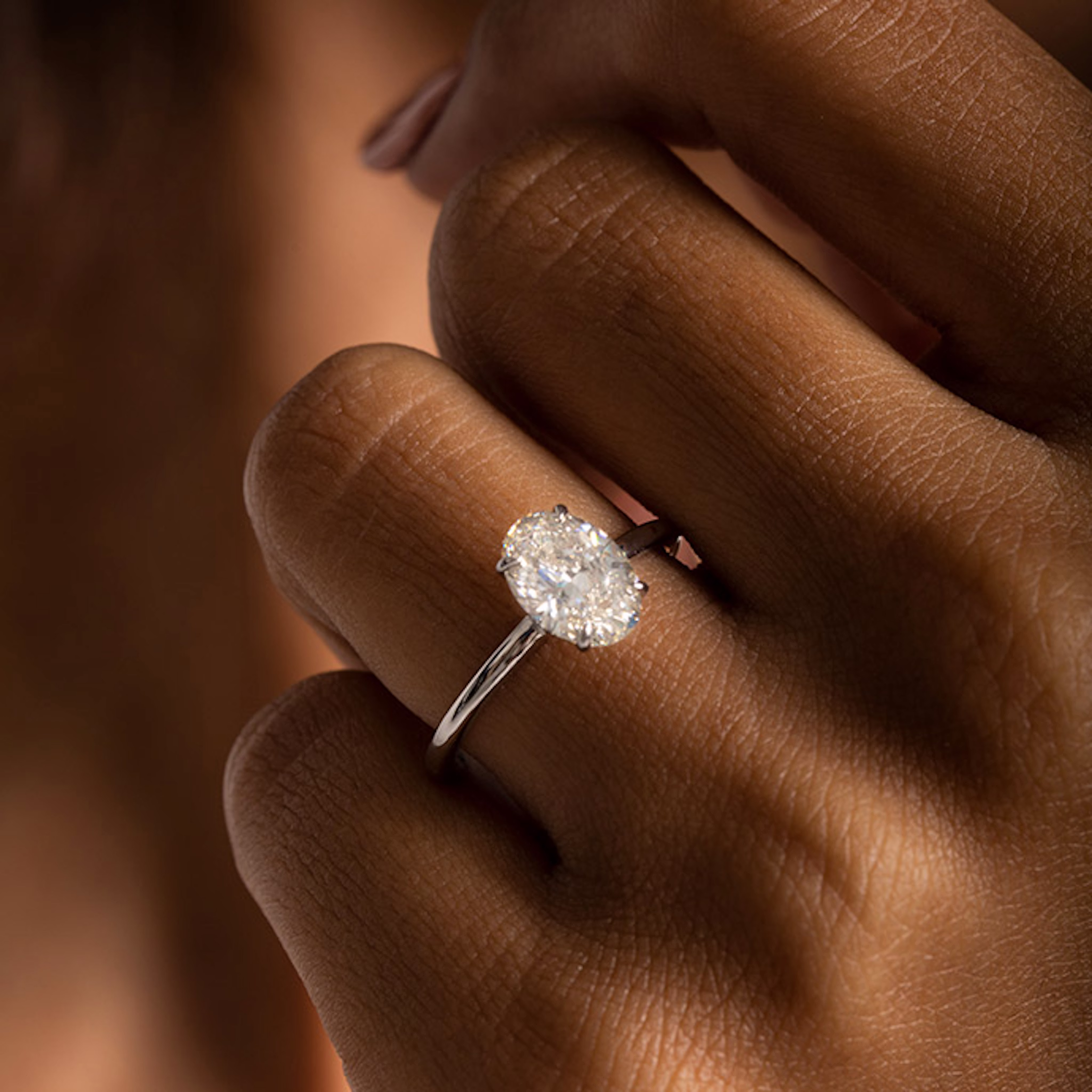 An oval-shaped VRAI created diamond ring is on the ring finger of someone’s hand.
