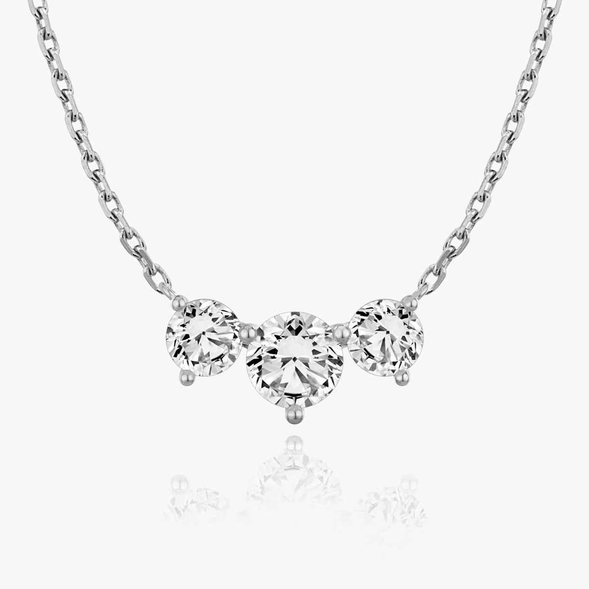 A close-up of an arc necklace with three large round stones in white gold.