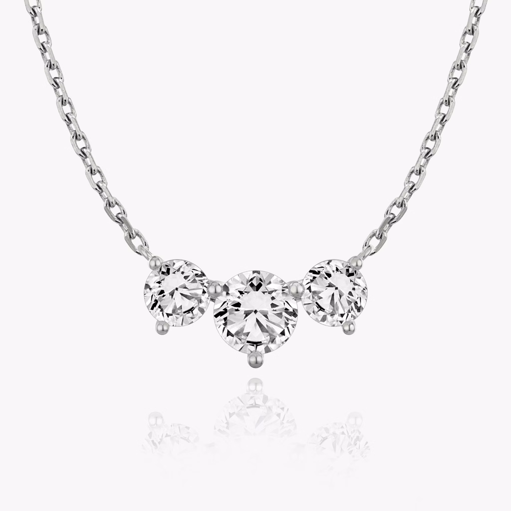 A close-up of an arc necklace with three large round stones in white gold.