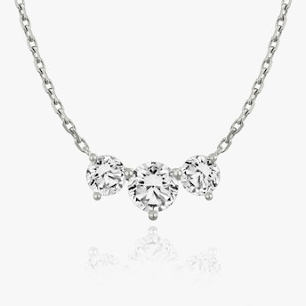 A close-up of an arc necklace with three large round stones in white gold.