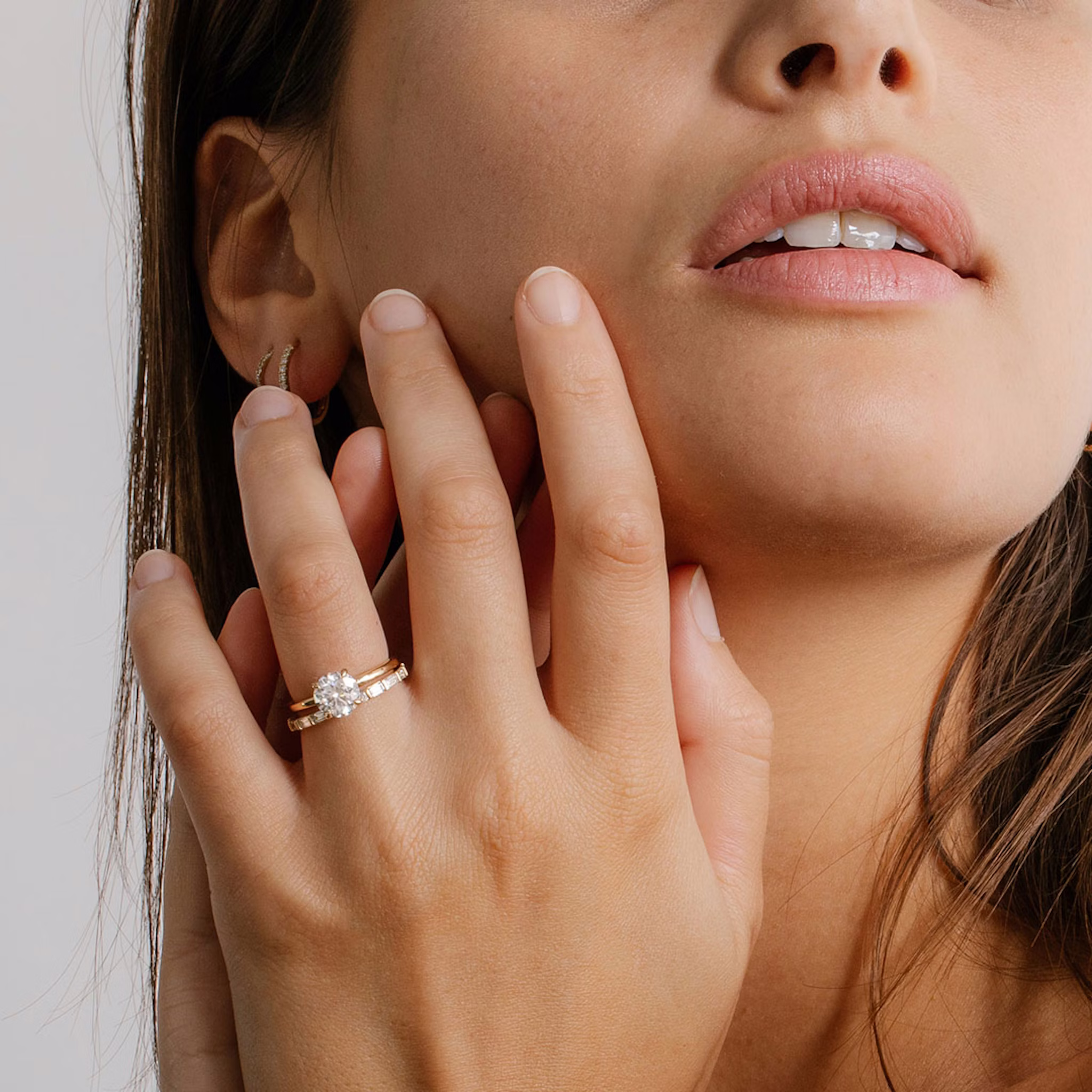 Hand wearing a classic four-prong yellow gold solitaire engagement ring with a round-cut diamond, styled elegantly.