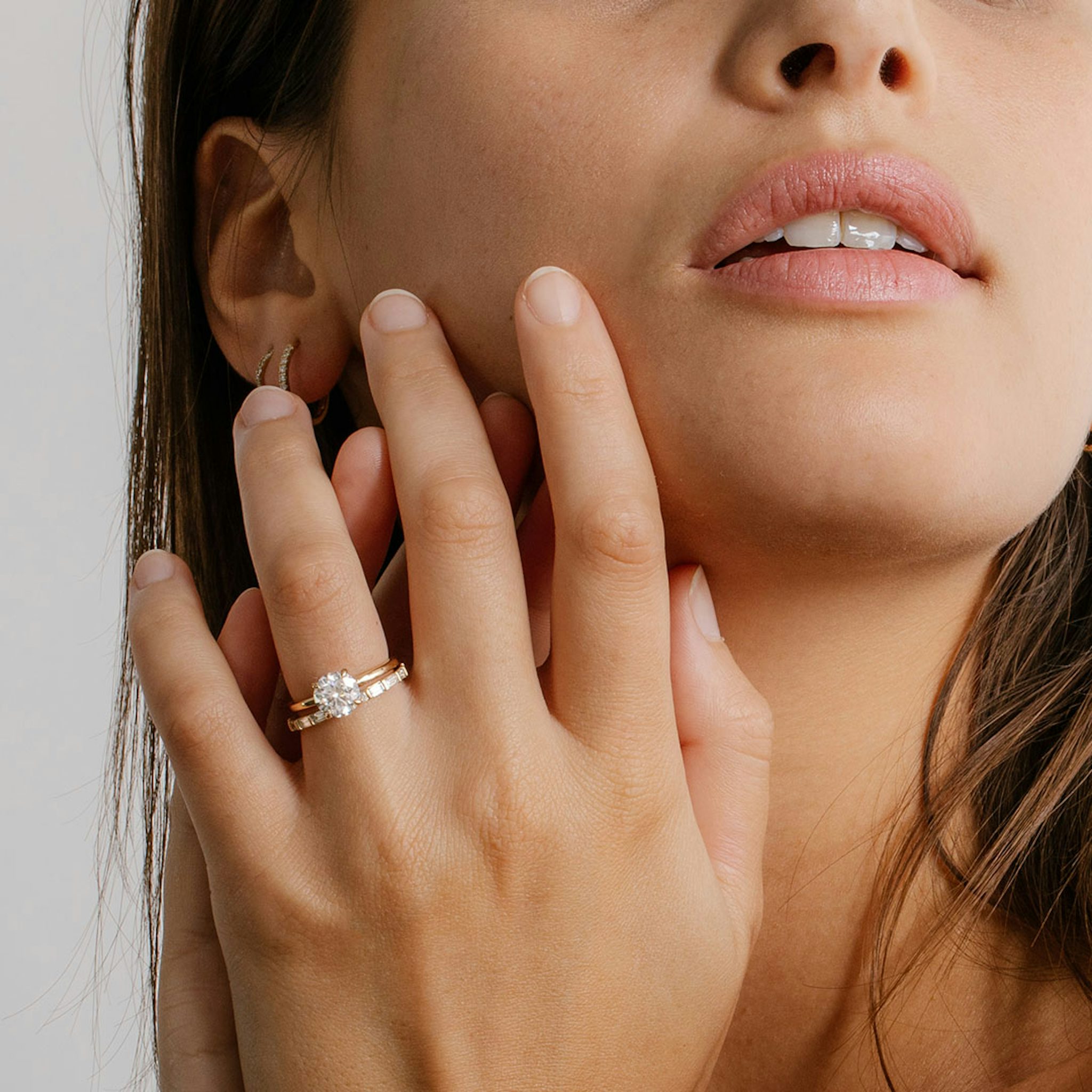 Hand wearing a classic four-prong yellow gold solitaire engagement ring with a round-cut diamond, styled elegantly.