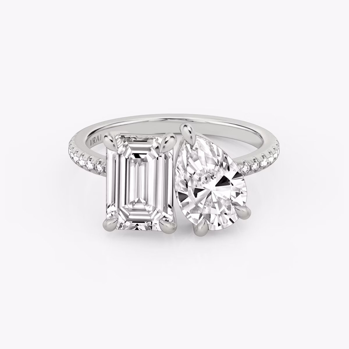 Toi et Moi ring with emerald and pear-cut diamonds on a pavé white gold band, designed for a modern yet elegant engagement look.