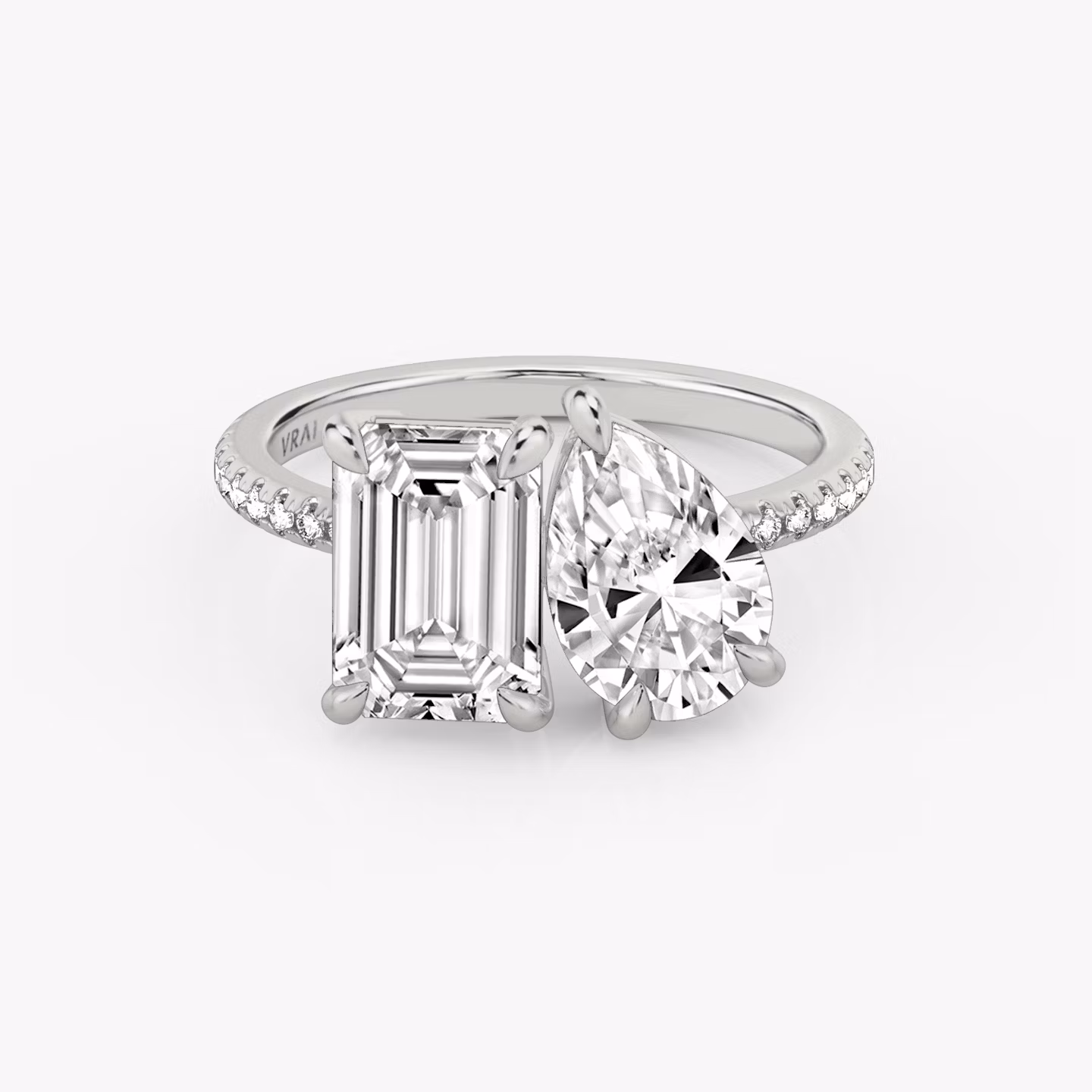 Toi et Moi ring with emerald and pear-cut diamonds on a pavé white gold band, designed for a modern yet elegant engagement look.