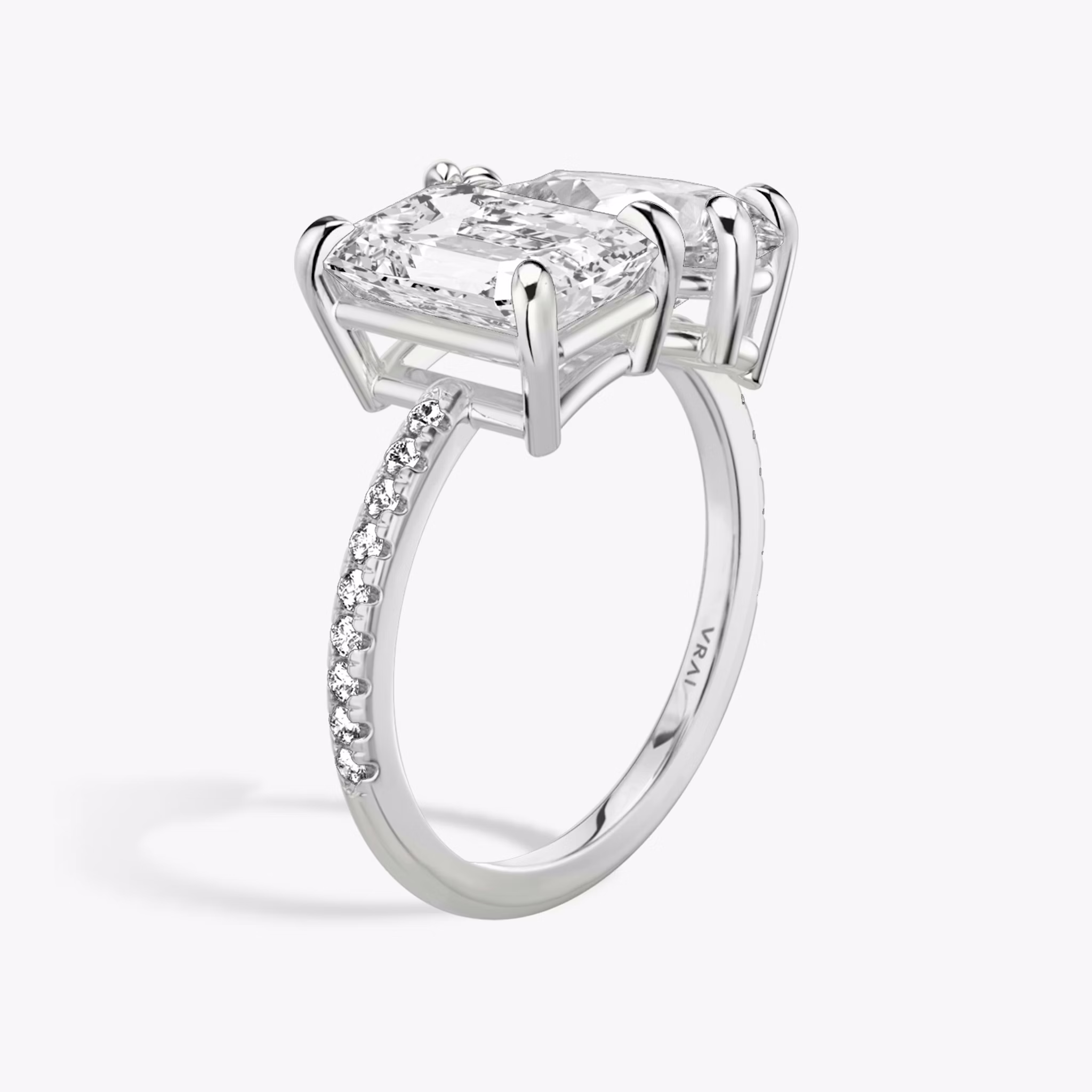 Toi et Moi ring with emerald and pear-cut diamonds on a pavé white gold band, designed for a modern yet elegant engagement look.