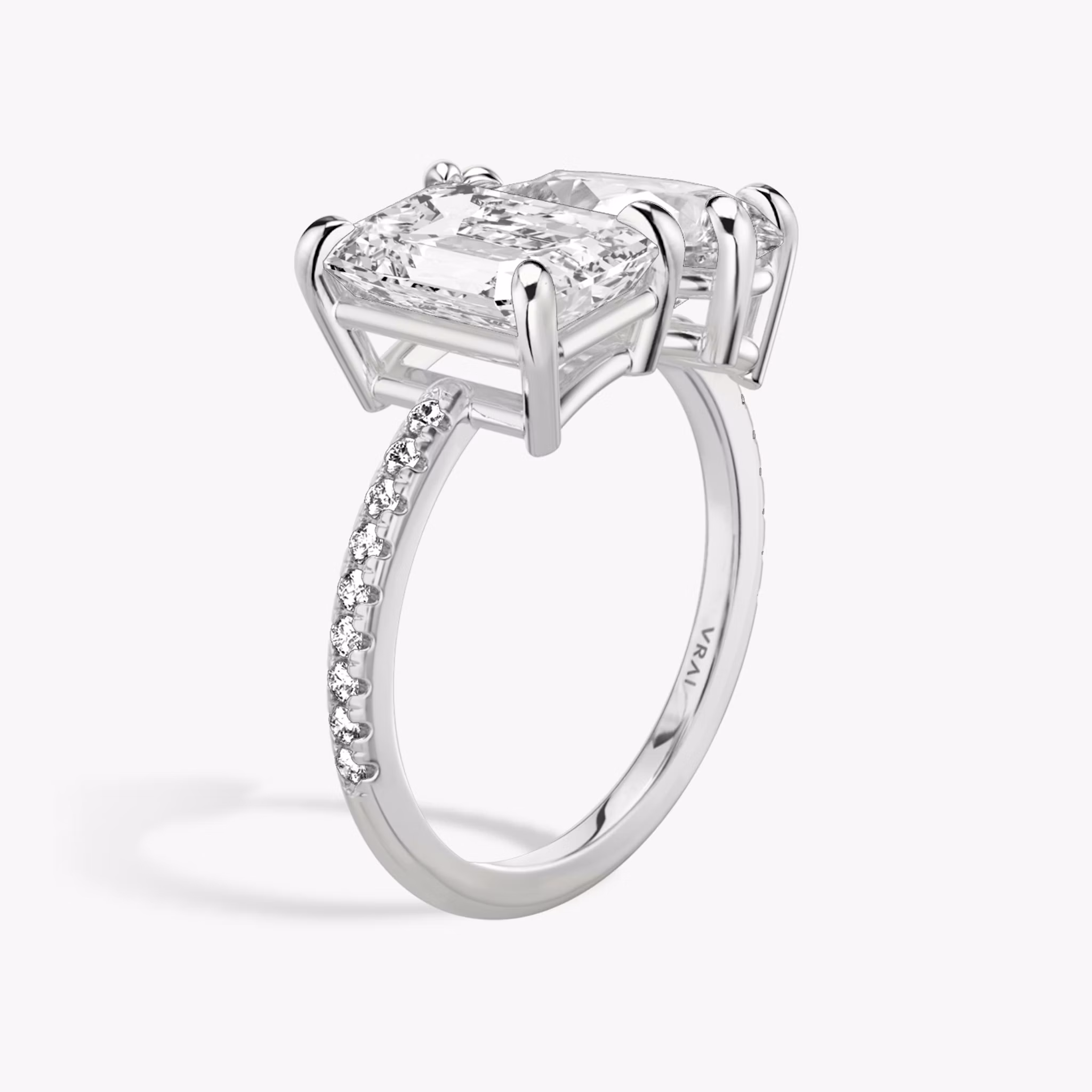 Toi et Moi ring with emerald and pear-cut diamonds on a pavé white gold band, designed for a modern yet elegant engagement look.