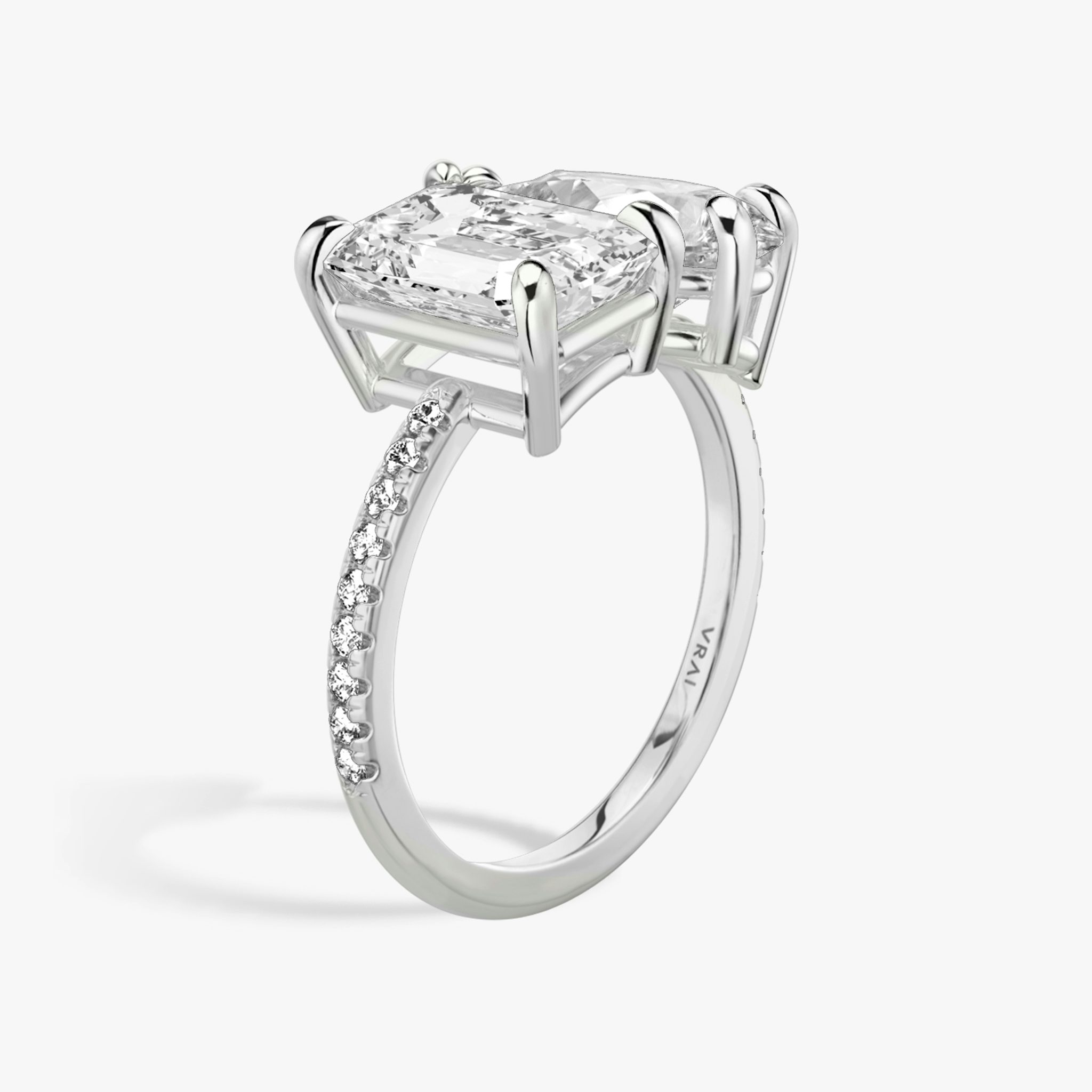 Toi et Moi ring with emerald and pear-cut diamonds on a pavé white gold band, designed for a modern yet elegant engagement look.