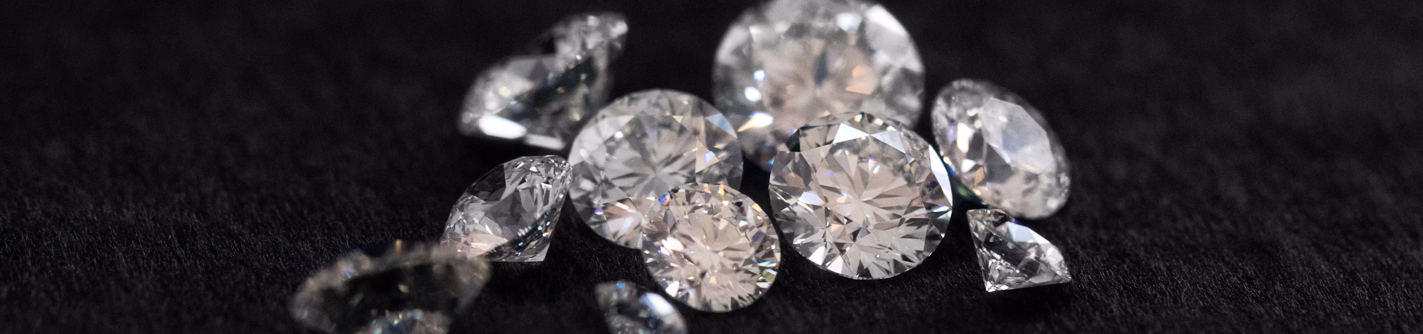 Multiple Round Brilliant cut diamonds on a black background.