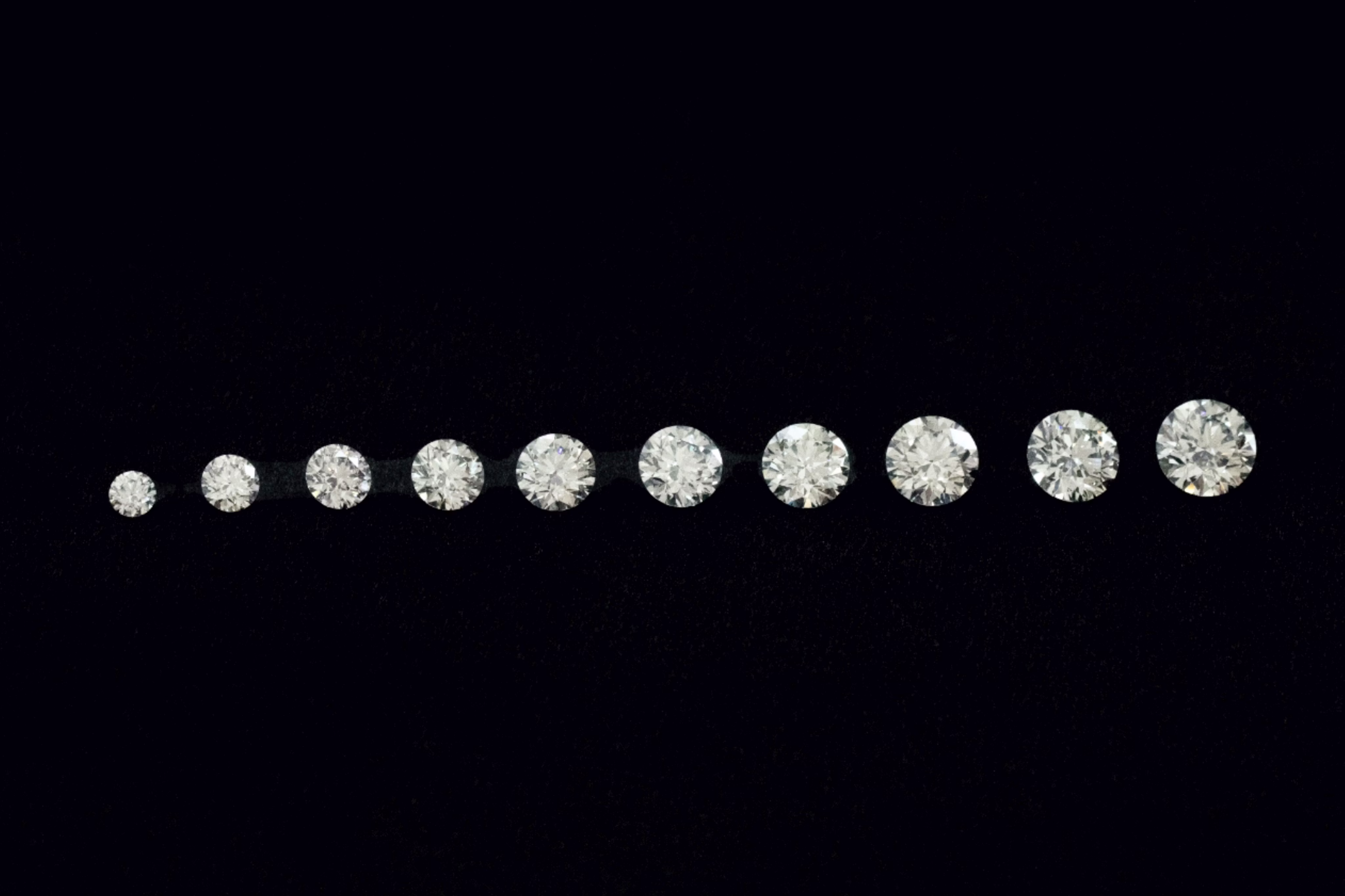 A row of Round Brilliant cut diamonds of various carat weights and sizes lined up in a row