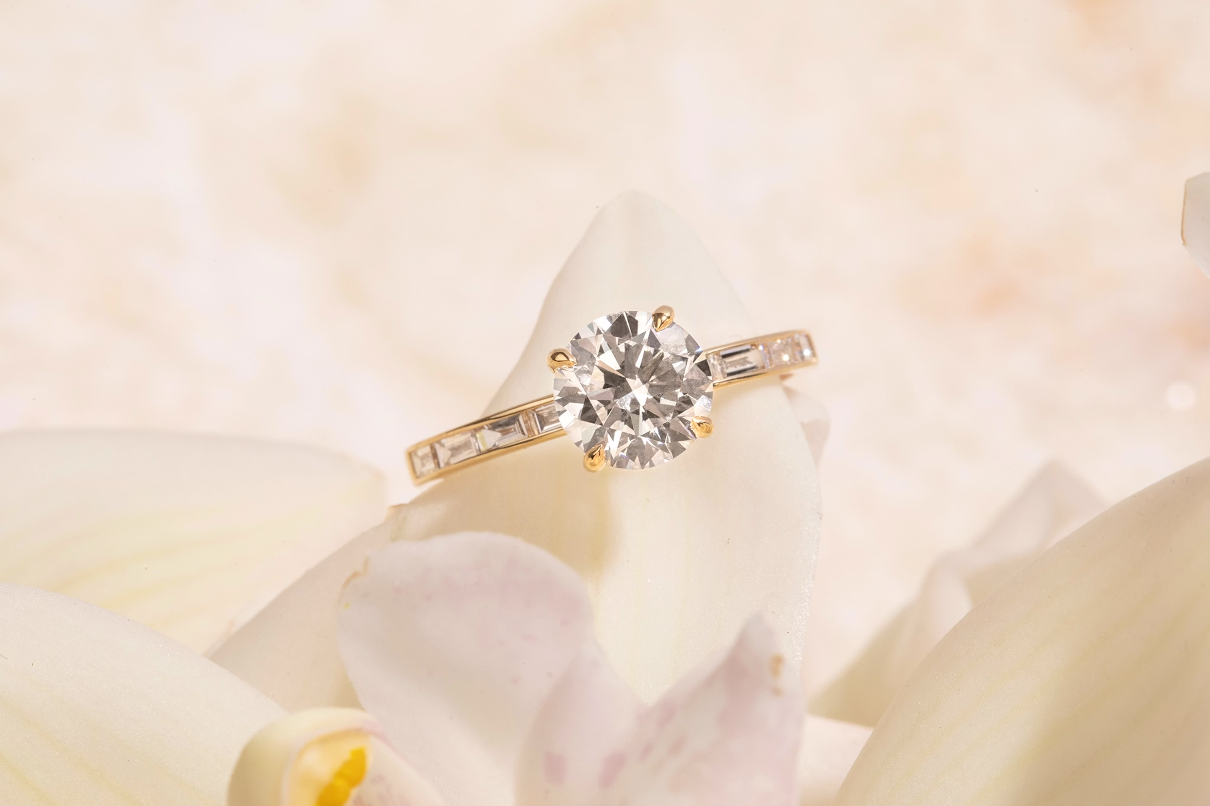 round brilliant cut diamond engagement ring with baguette shaped stones in yellow gold band