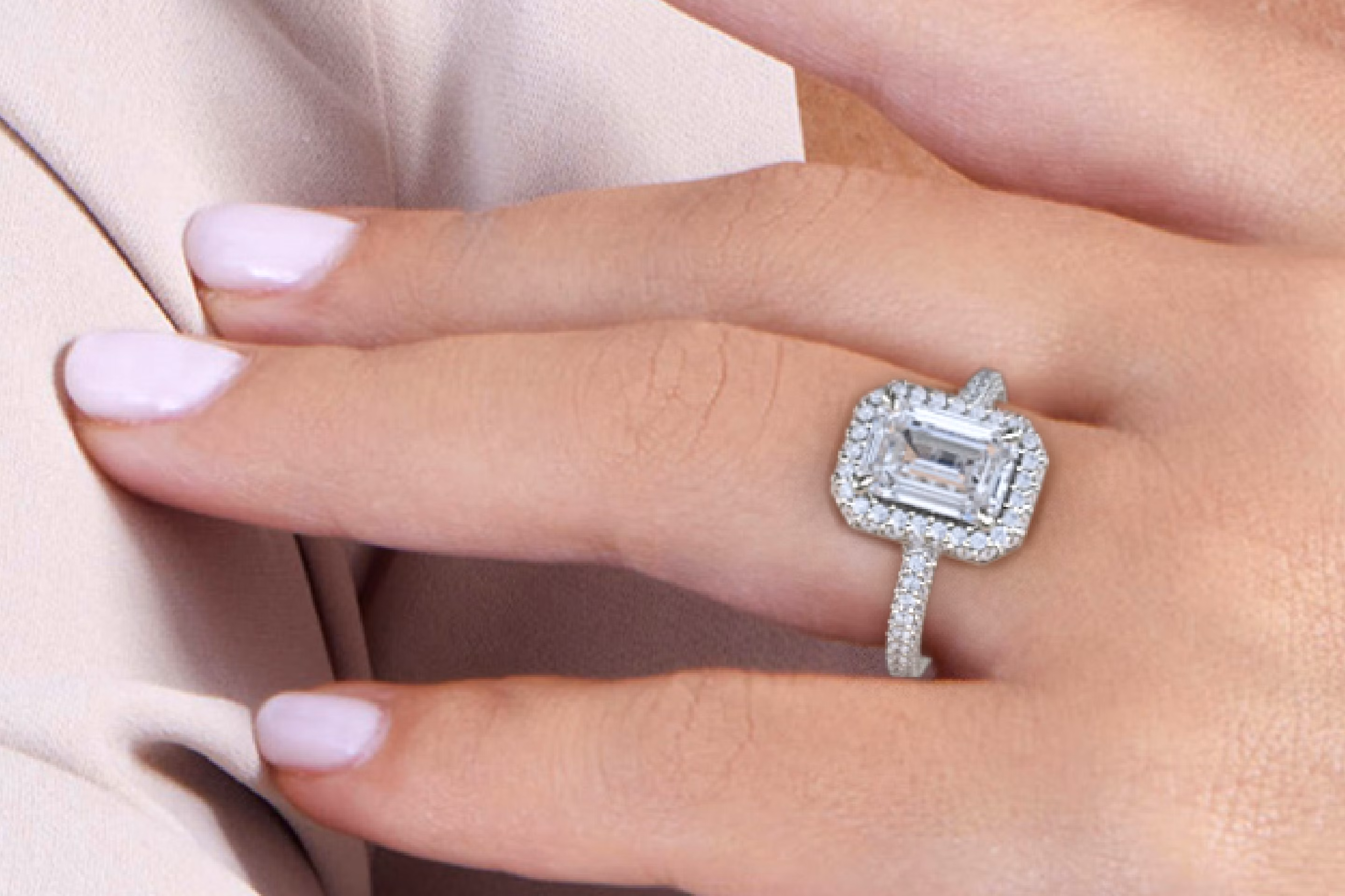 a hand with a VRAI created Emerald cut diamond Halo engagement ring in platinum