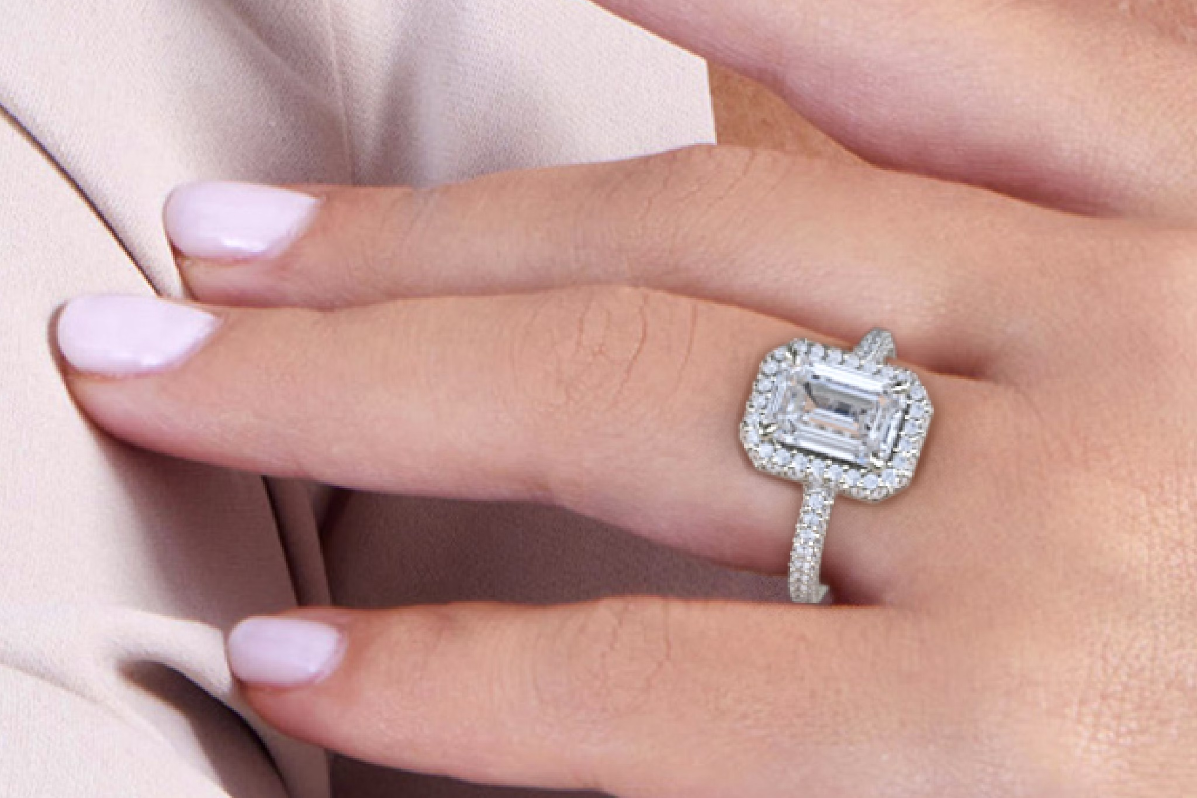 a hand with a VRAI created Emerald cut diamond Halo engagement ring in platinum