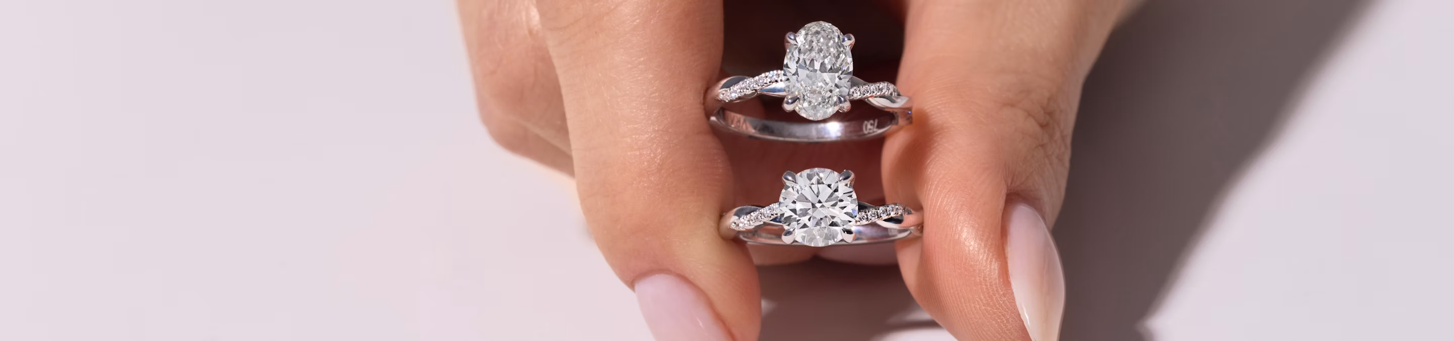 A hand holding two platinum engagement rings