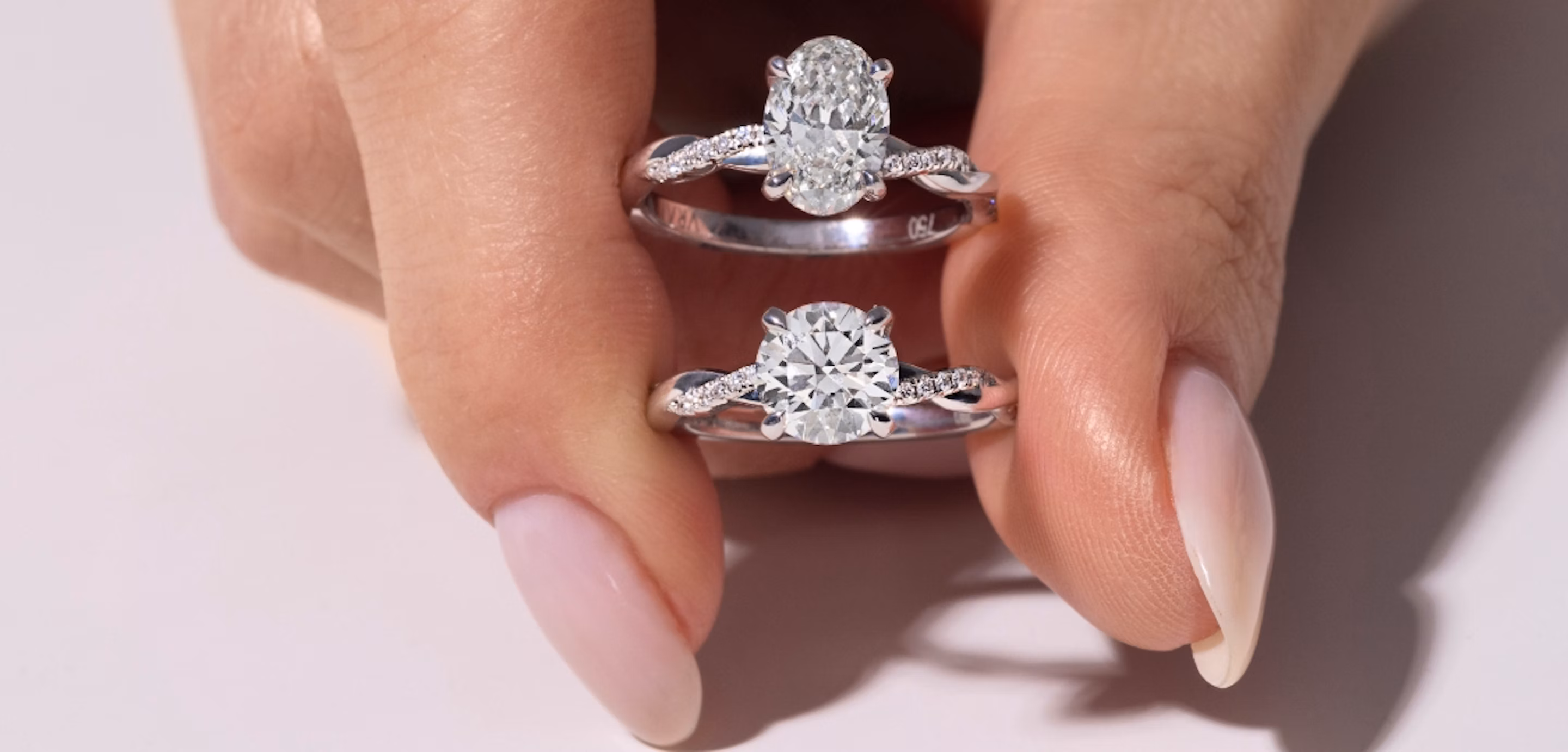 A hand holding two platinum engagement rings