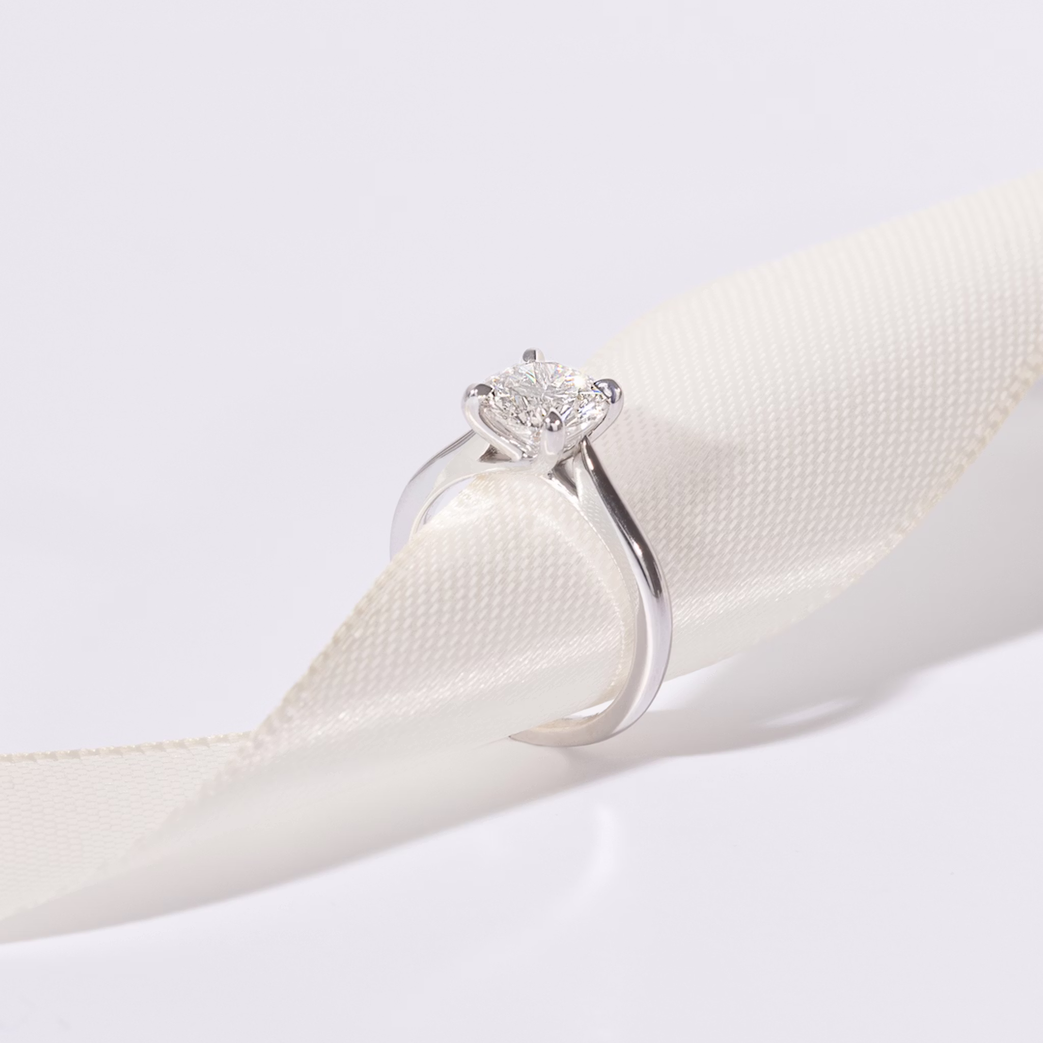 White gold diamond engagement ring on a piece of white ribbon